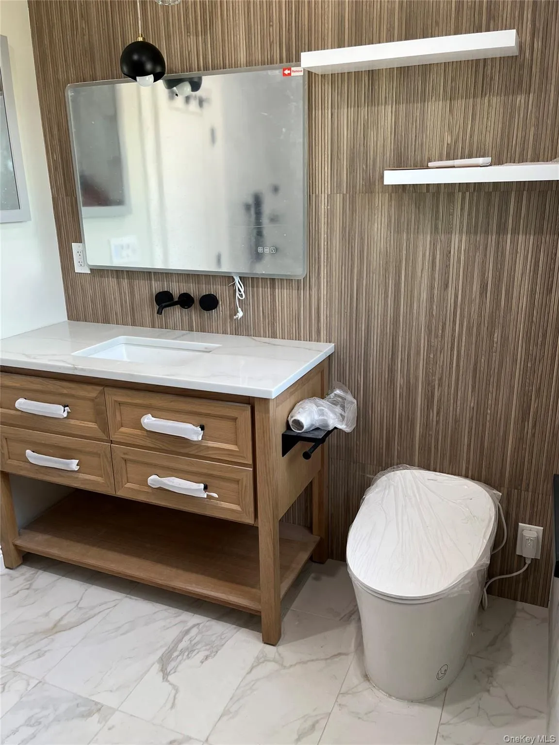 Bathroom with marble look tiles, vanity, and wooden walls Bathroom with marble look tiles, vanity, and wooden walls