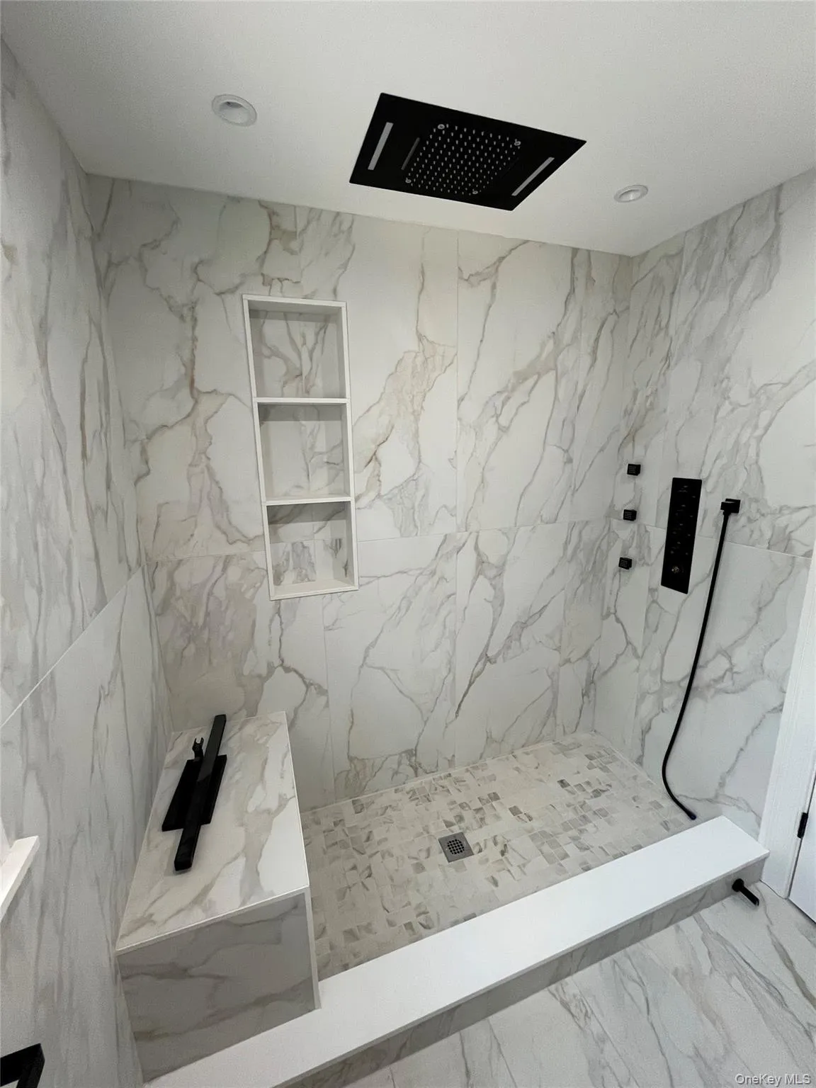 Bathroom with a marble finish shower, marble finish floors, and recessed lighting Bathroom with a marble finish shower, marble finish floors, and recessed lighting