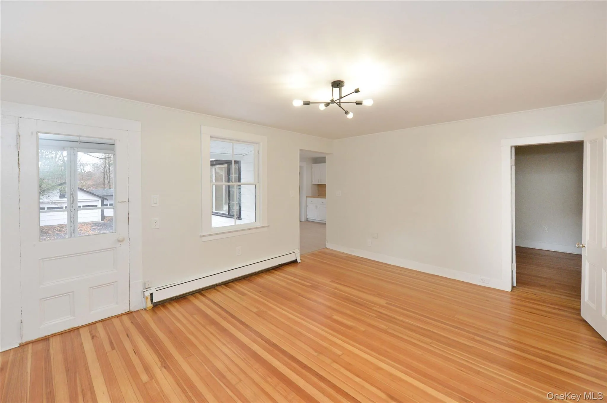 Entrance foyer featuring healthy amount of natural light, a baseboard heating unit, a chandelier, and light wood finished floors Entrance foyer featuring healthy amount of natural light, a baseboard heating unit, a chandelier, and light wood finished floors
