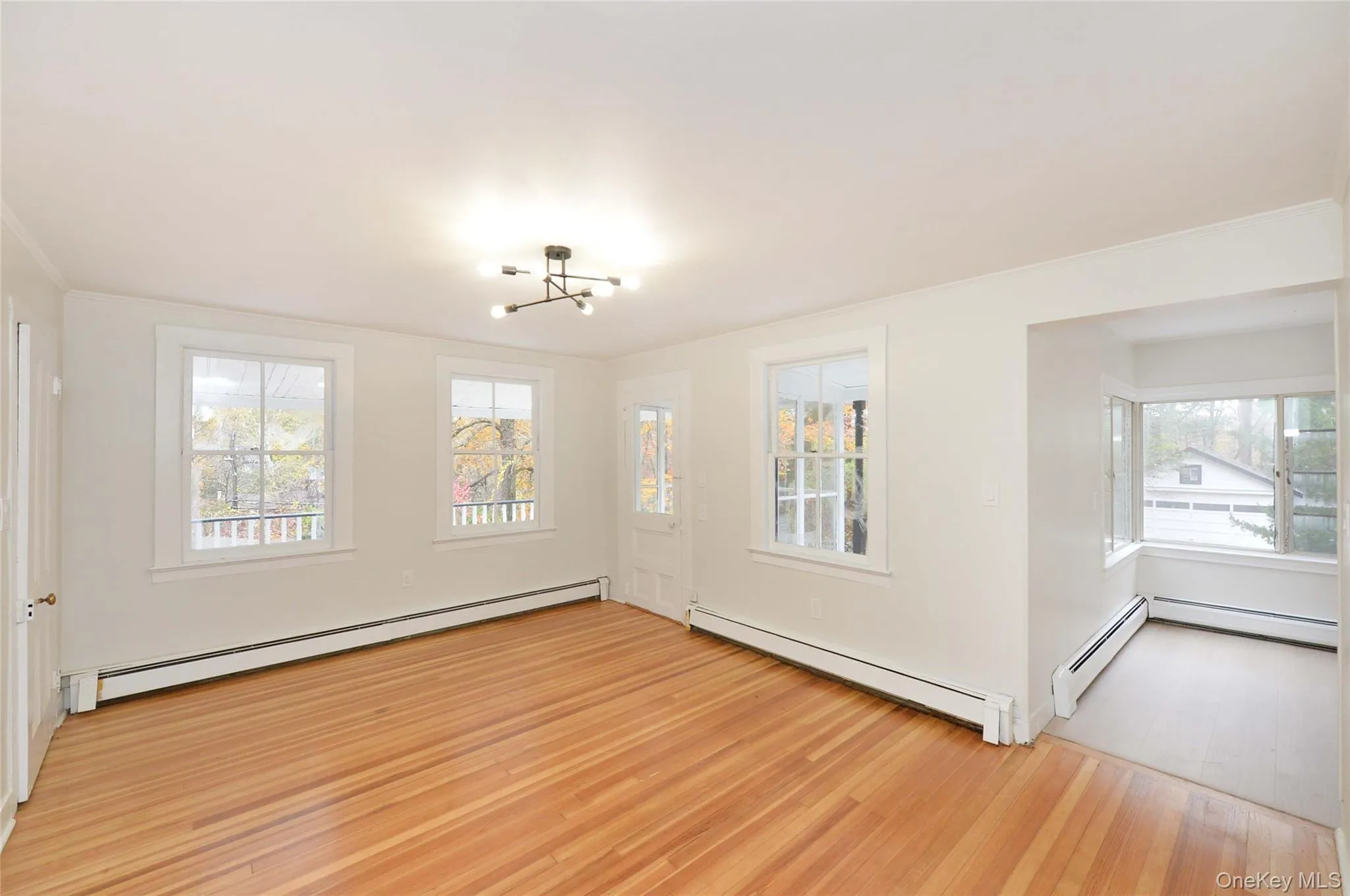 Unfurnished room with a baseboard heating unit, a baseboard radiator, light wood-style flooring, a chandelier, and crown molding Unfurnished room with a baseboard heating unit, a baseboard radiator, light wood-style flooring, a chandelier, and crown molding