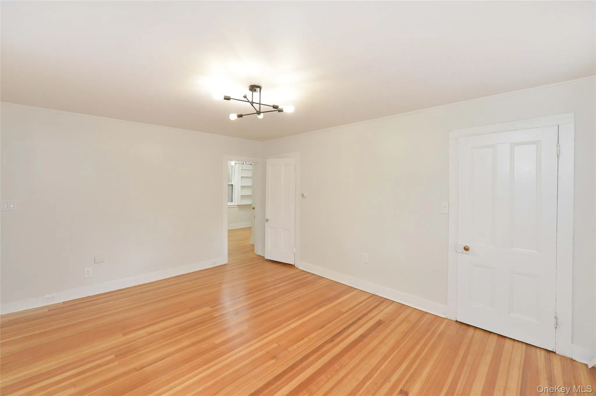 Empty room featuring a chandelier and light wood-style flooring Empty room featuring a chandelier and light wood-style flooring