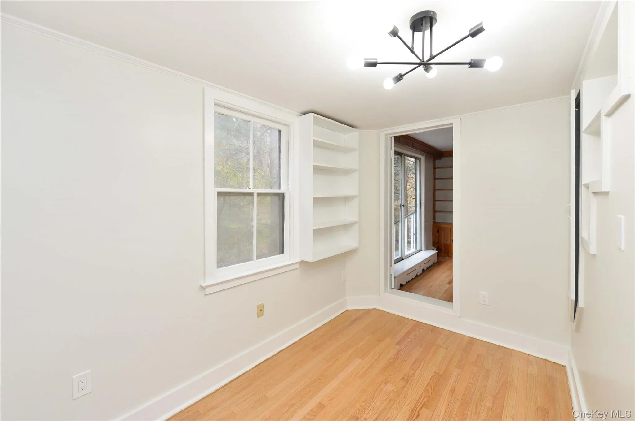 Empty room with a chandelier and light wood-style floors Empty room with a chandelier and light wood-style floors