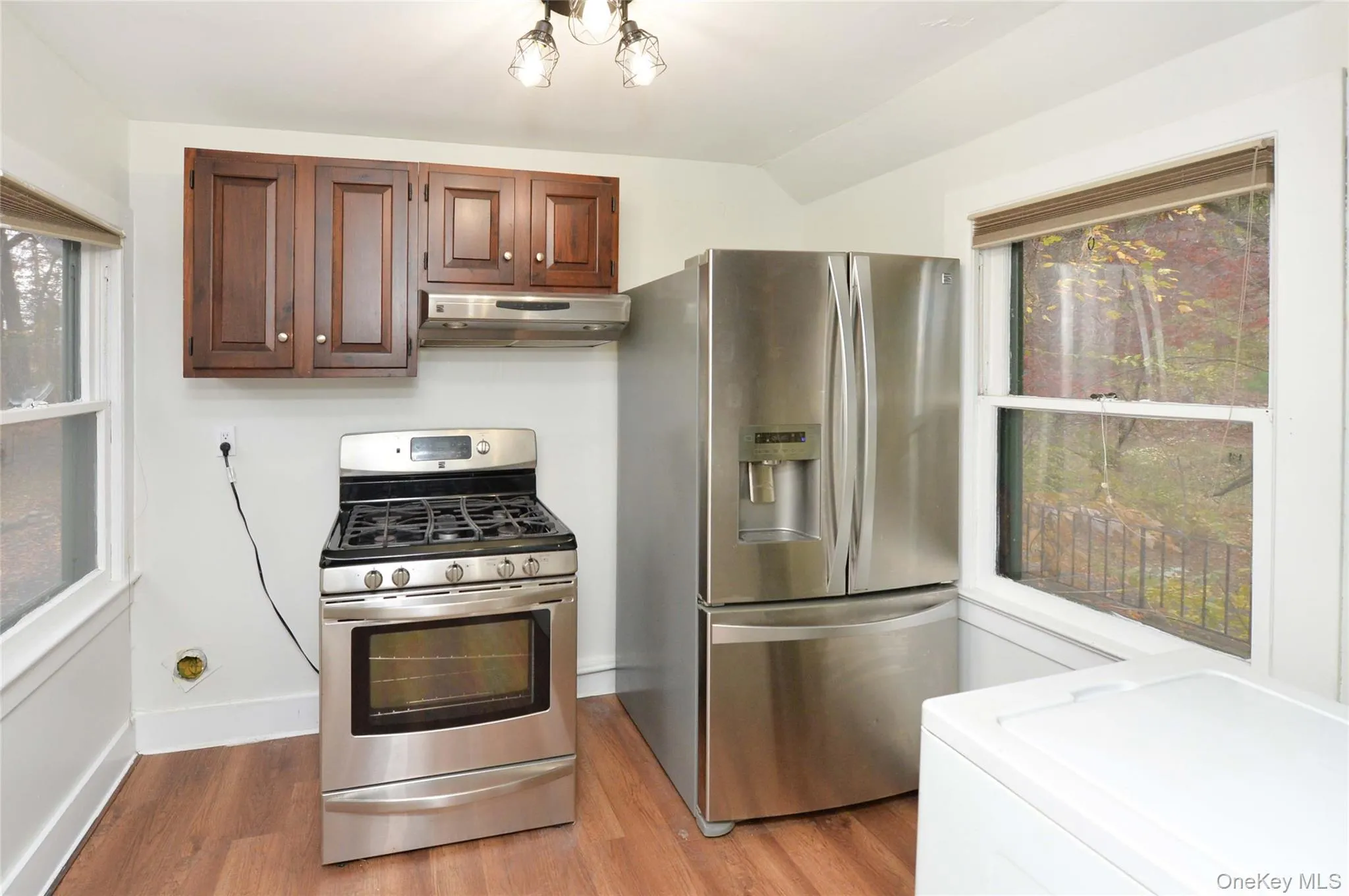 Kitchen with stainless steel appliances, washer / clothes dryer, light wood-type flooring, and under cabinet range hood Kitchen with stainless steel appliances, washer / clothes dryer, light wood-type flooring, and under cabinet range hood