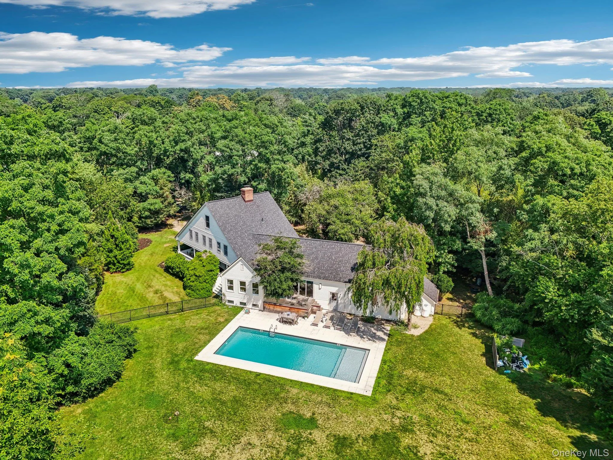 View from above of property featuring a forest and a pool View from above of property featuring a forest and a pool