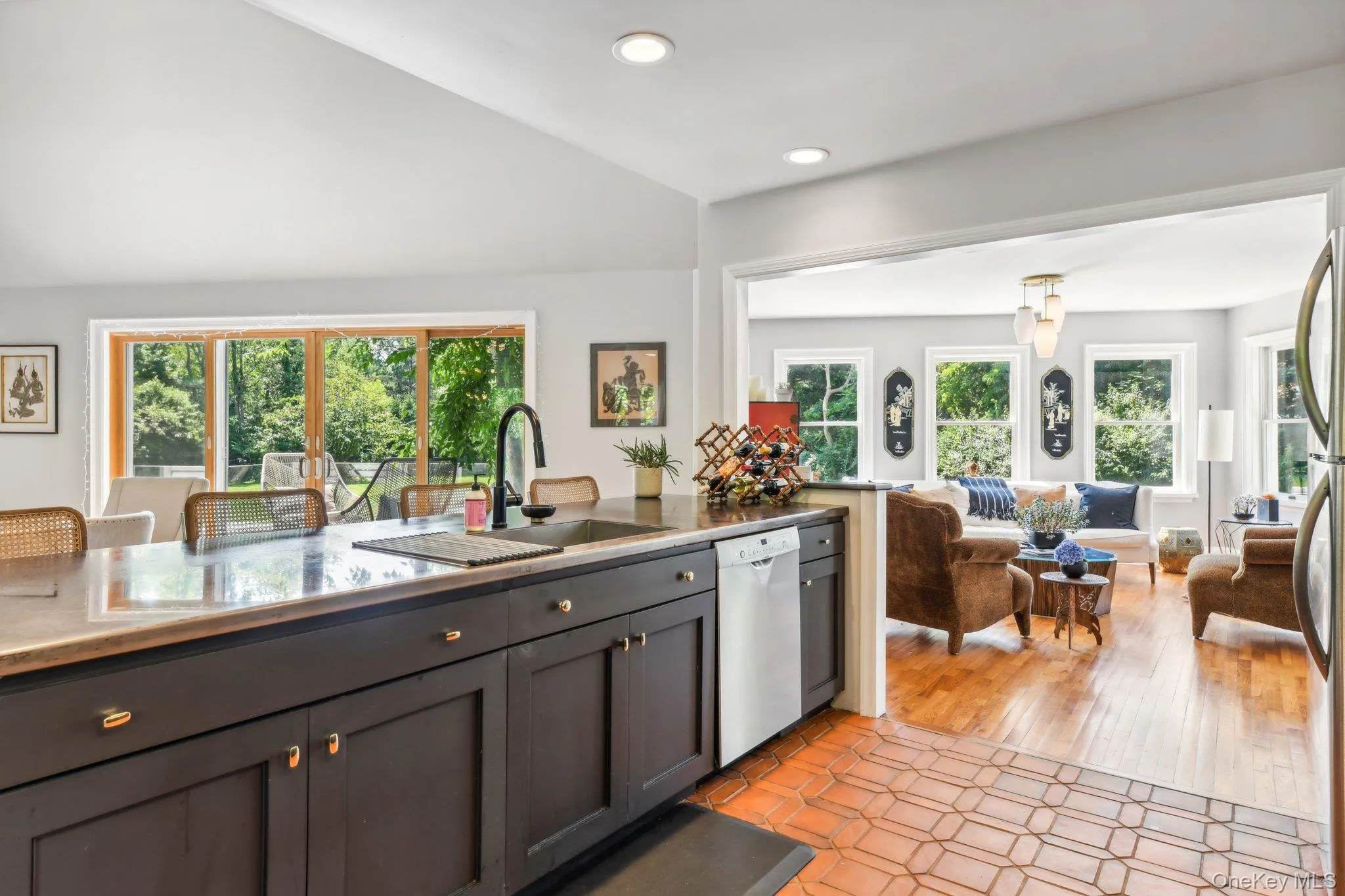 Kitchen with plenty of natural light, white dishwasher, lofted ceiling, gray cabinetry, and open floor plan Kitchen with plenty of natural light, white dishwasher, lofted ceiling, gray cabinetry, and open floor plan
