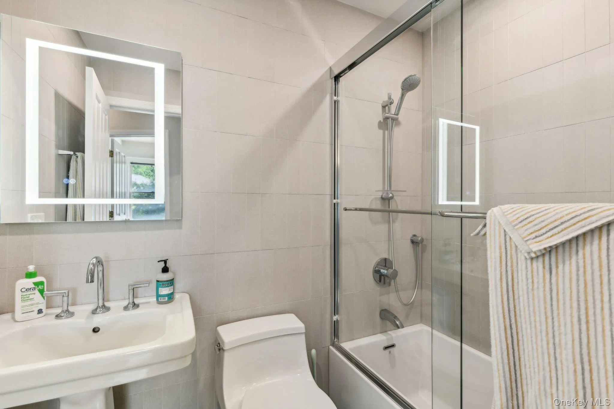 Full bathroom with enclosed tub / shower combo and tile walls Full bathroom with enclosed tub / shower combo and tile walls