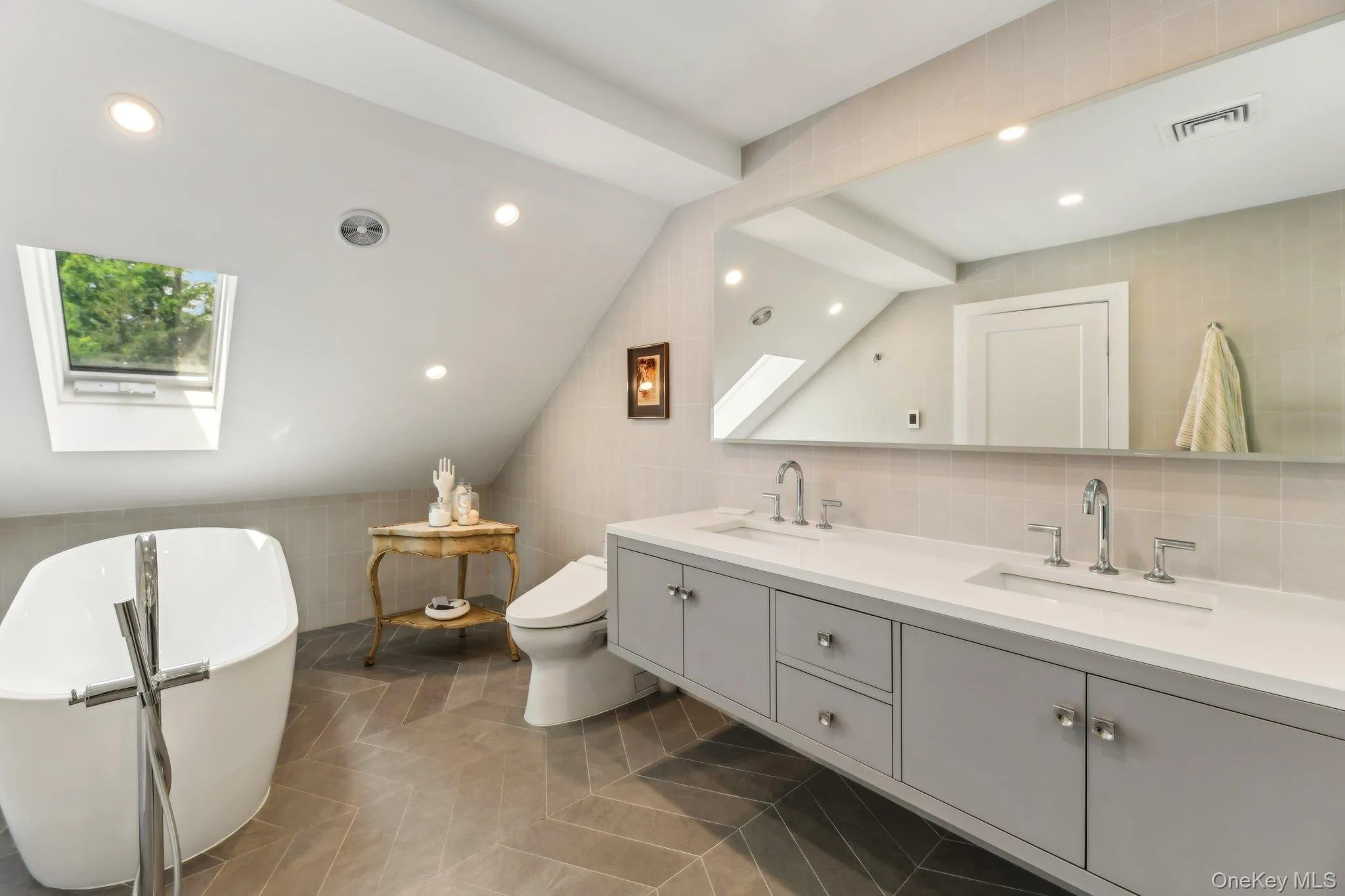 Full bathroom featuring a skylight, lofted ceiling, tile walls, double vanity, and recessed lighting Full bathroom featuring a skylight, lofted ceiling, tile walls, double vanity, and recessed lighting