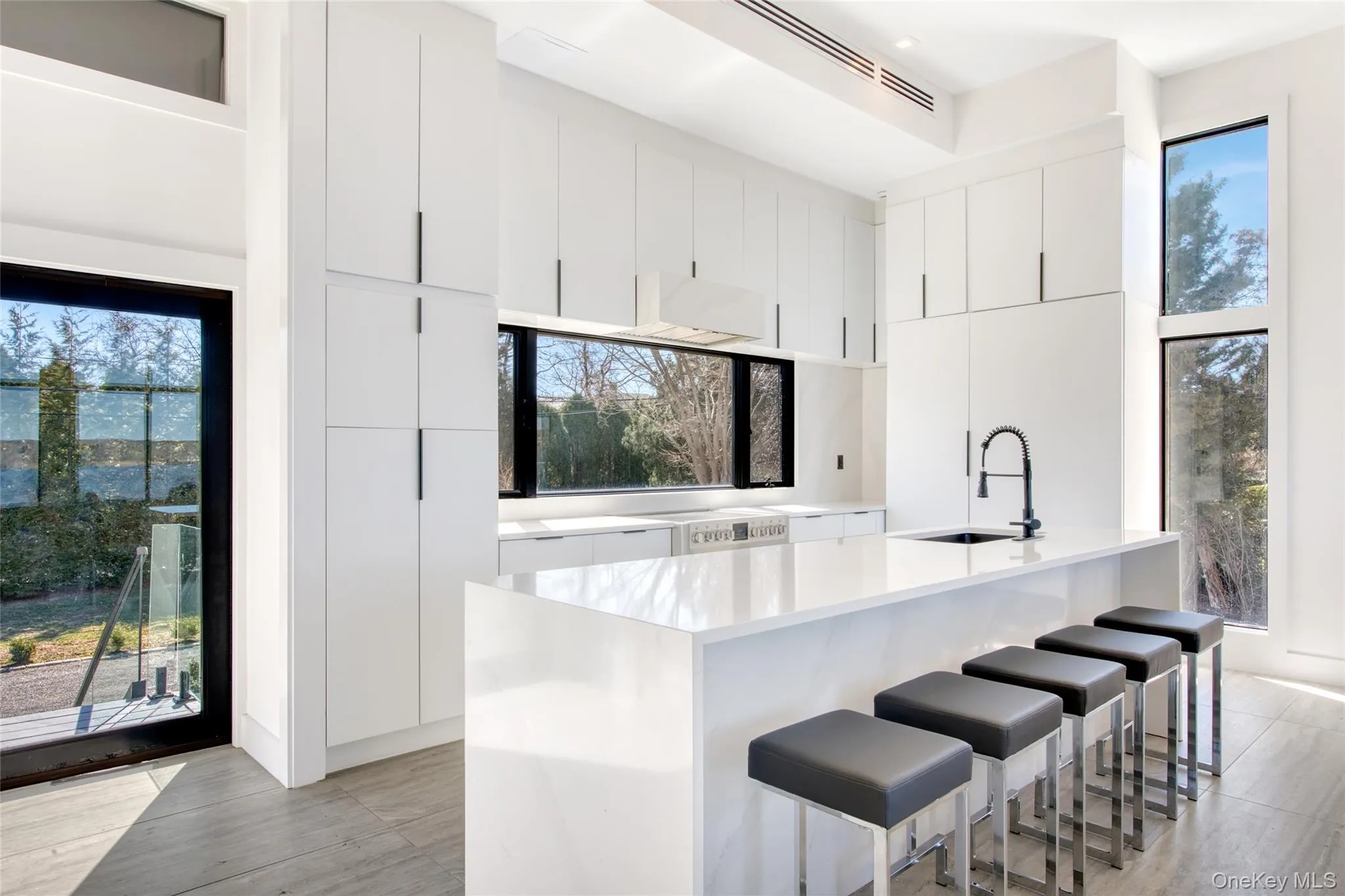Kitchen featuring light countertops, modern cabinets, a kitchen bar, white cabinetry, and a sink Kitchen featuring light countertops, modern cabinets, a kitchen bar, white cabinetry, and a sink