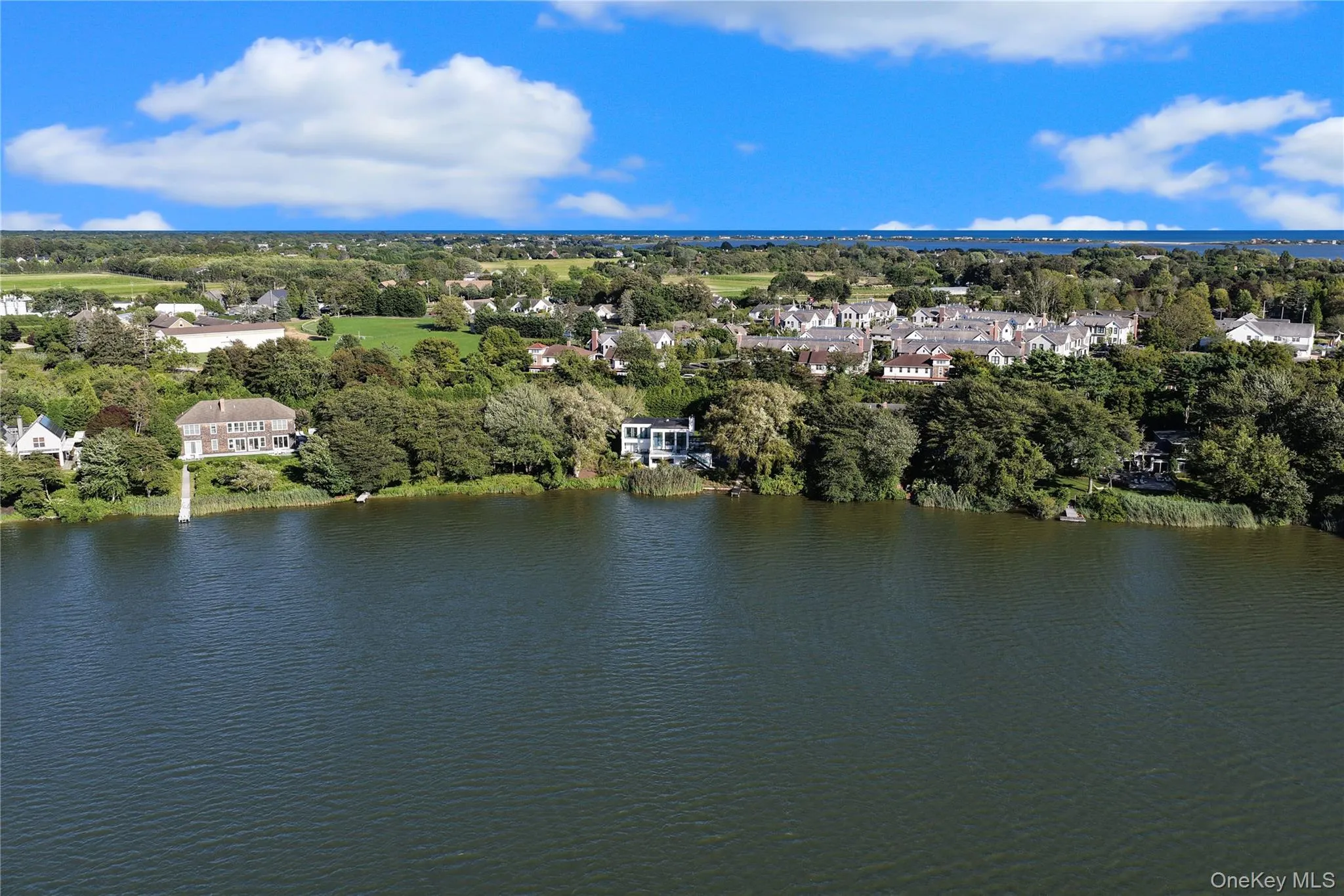 Aerial perspective of suburban area with a nearby body of water and a tree filled landscape Aerial perspective of suburban area with a nearby body of water and a tree filled landscape