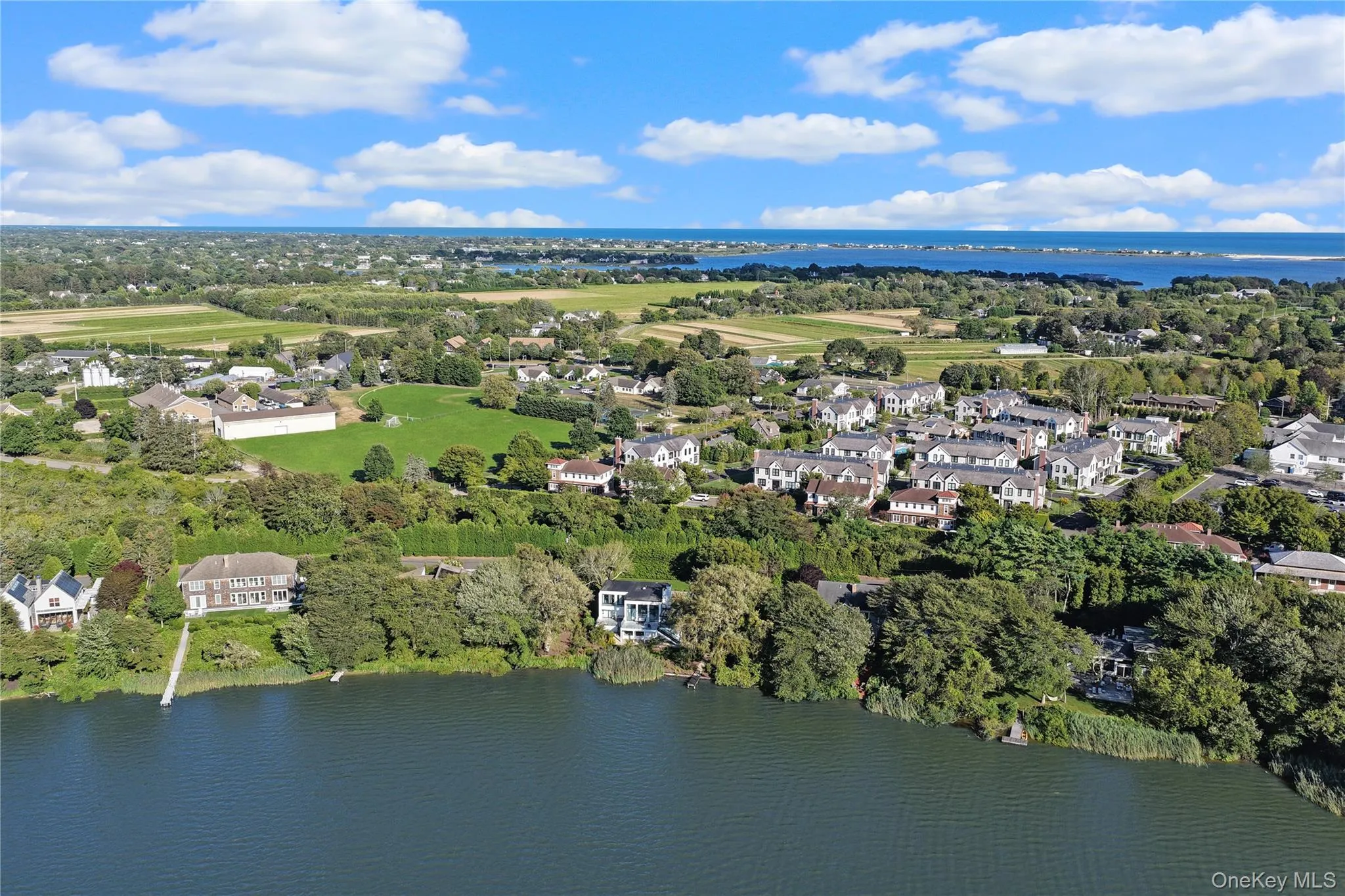 Aerial perspective of suburban area with a nearby body of water and a tree filled landscape Aerial perspective of suburban area with a nearby body of water and a tree filled landscape