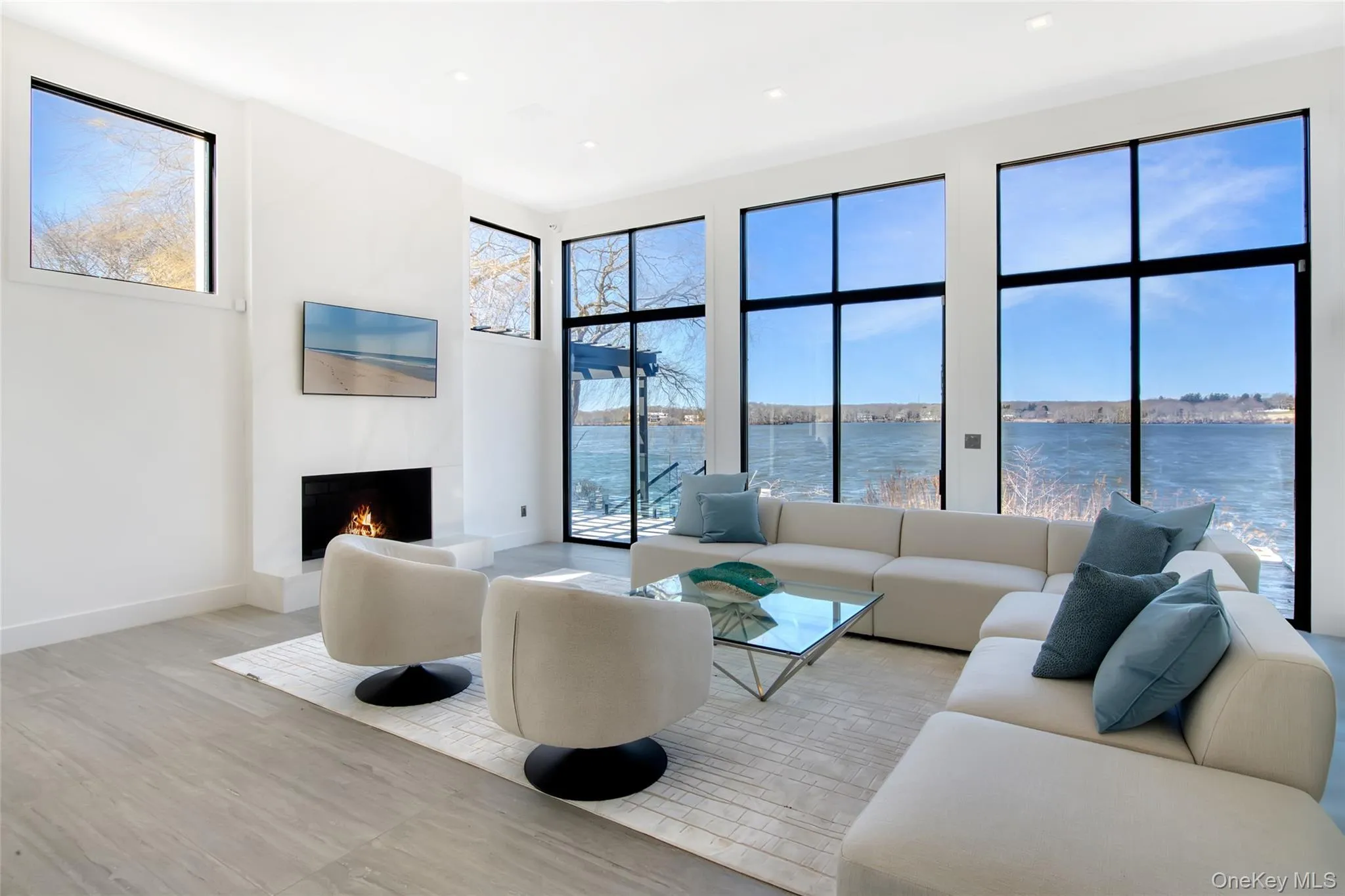 Living area with a healthy amount of sunlight, baseboards, a lit fireplace, and wood finished floors Living area with a healthy amount of sunlight, baseboards, a lit fireplace, and wood finished floors