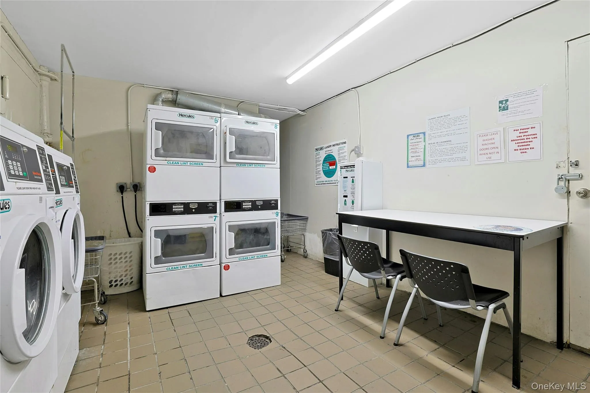 Community laundry room with washing machine and dryer & clothes folding table Community laundry room with washing machine and dryer & clothes folding table