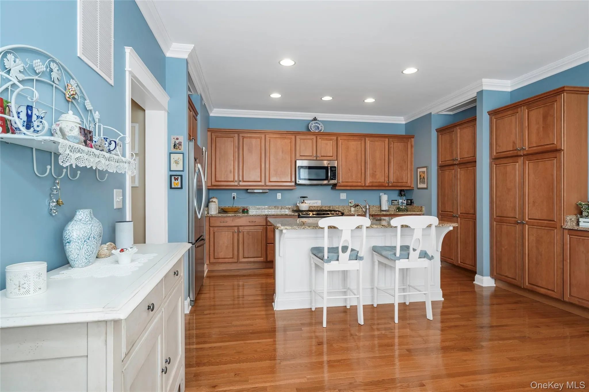 Kitchen with a breakfast bar area, crown molding, an island with sink, stainless steel appliances, and light stone counters Kitchen with a breakfast bar area, crown molding, an island with sink, stainless steel appliances, and light stone counters