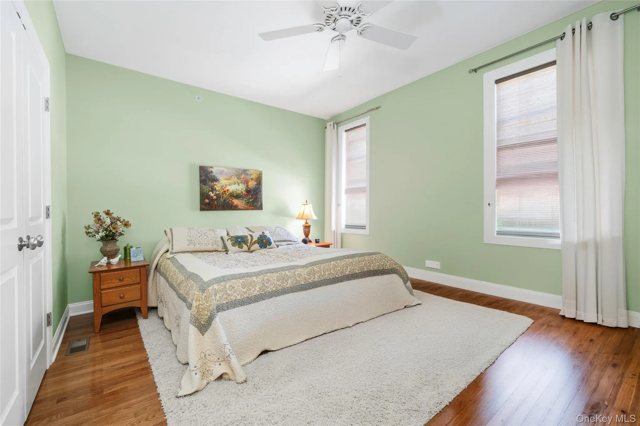 Bedroom 2 featuring multiple windows, wood finished floors, a closet, and a ceiling fan Bedroom 2 featuring multiple windows, wood finished floors, a closet, and a ceiling fan