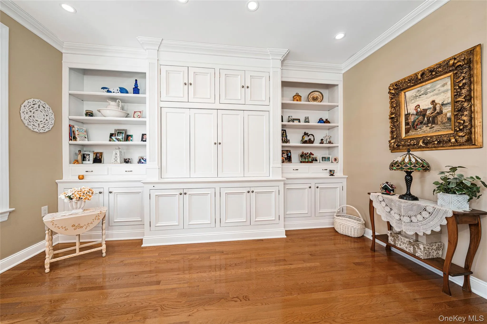 Living area featuring built in shelves, light wood finished floors, ornamental molding, and recessed lighting Living area featuring built in shelves, light wood finished floors, ornamental molding, and recessed lighting