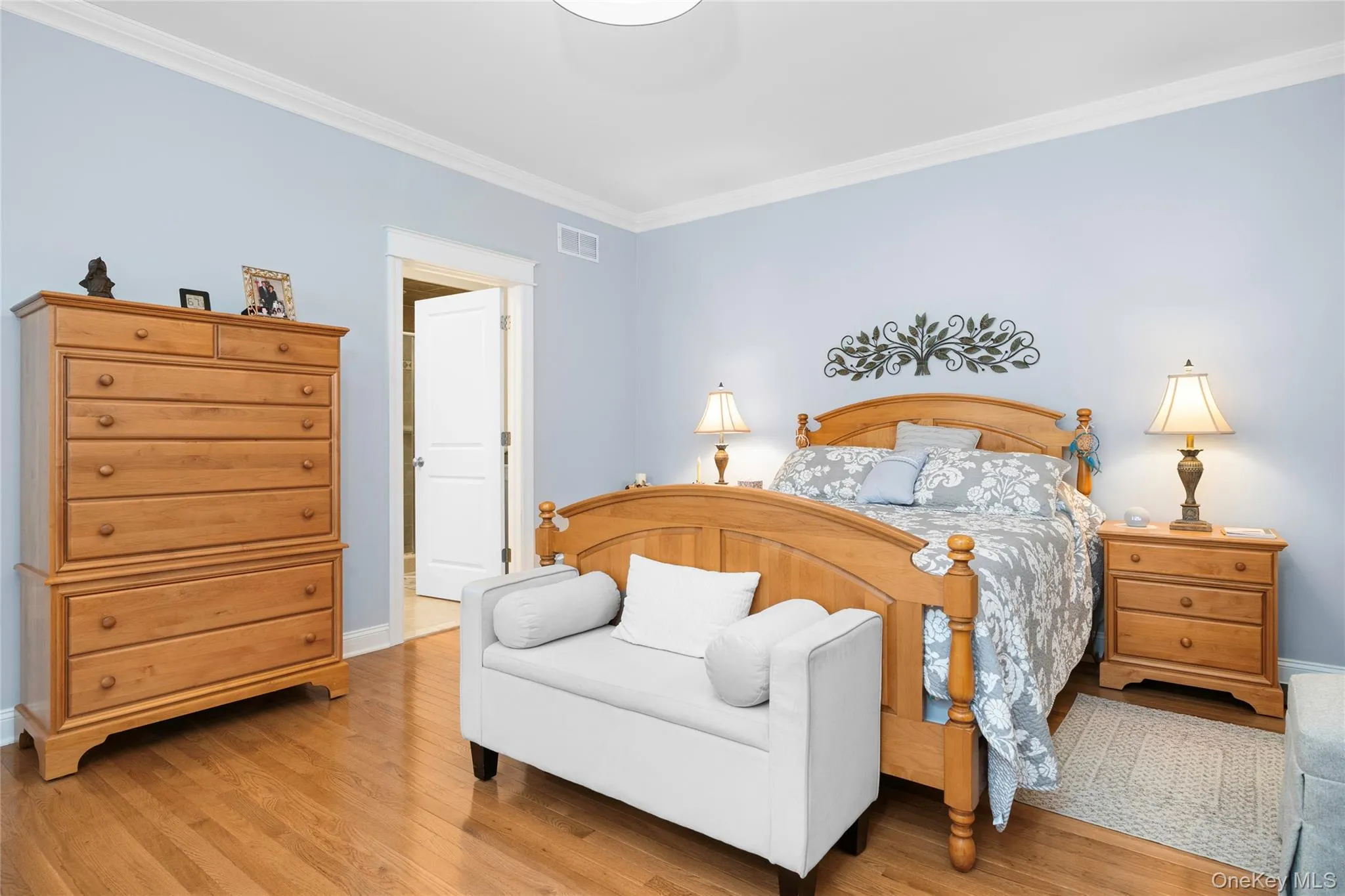 Bedroom featuring ornamental molding and wood finished floors and private bathroom. Bedroom featuring ornamental molding and wood finished floors and private bathroom.