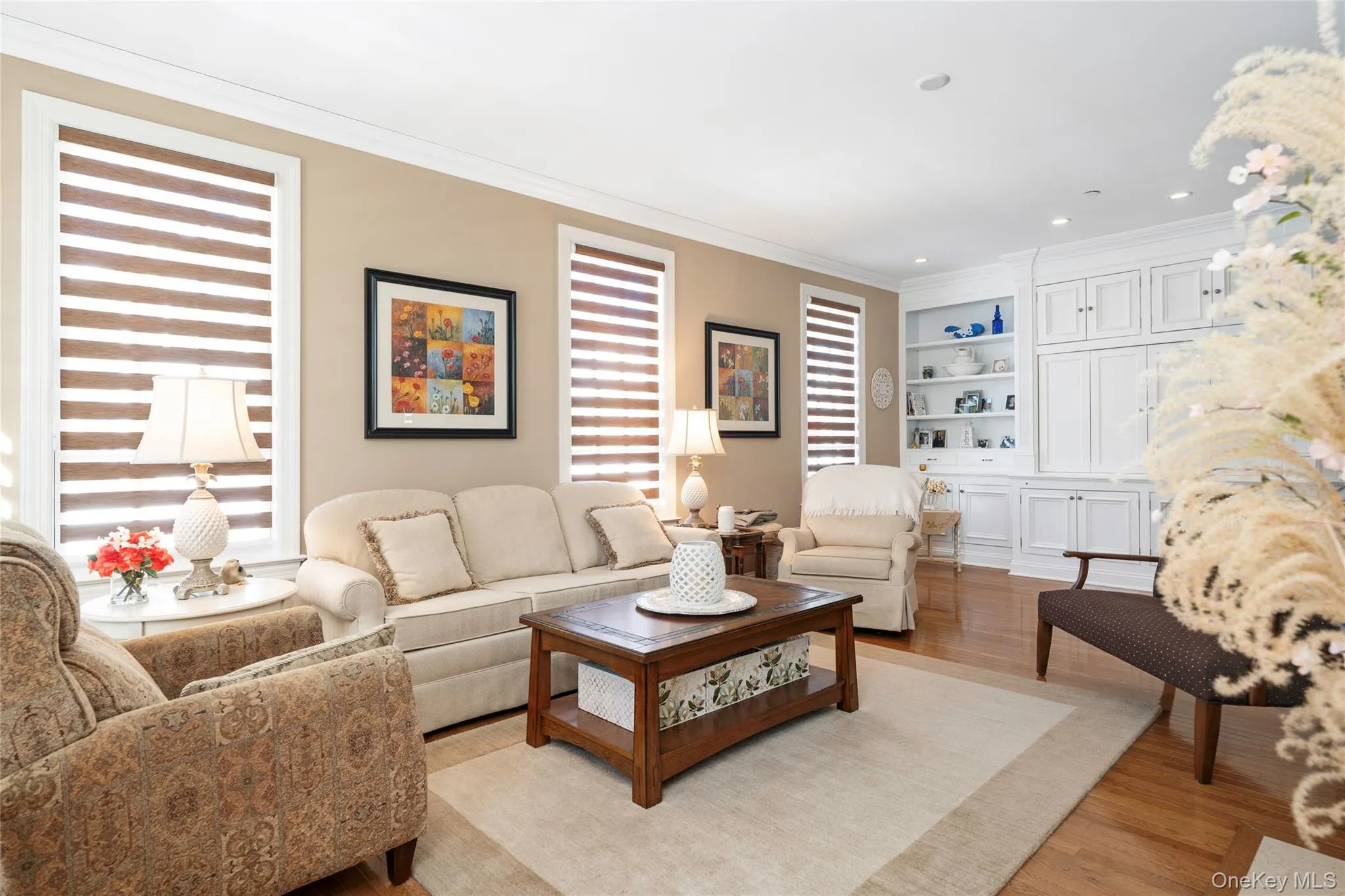 Living room with wood finished floors, built in features, ornamental molding, and recessed lighting Living room with wood finished floors, built in features, ornamental molding, and recessed lighting
