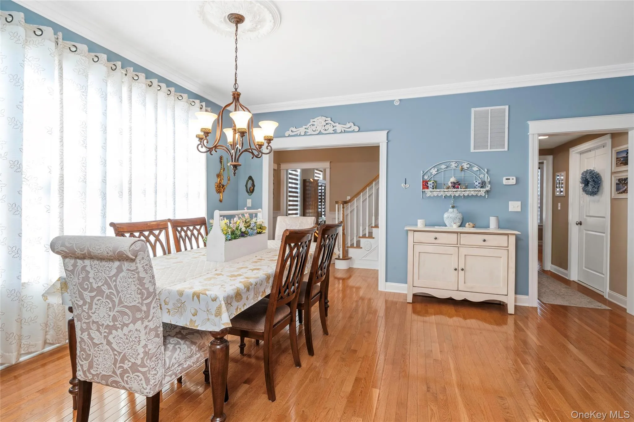 Dining space with light wood-style flooring, ornamental molding, and hanging lights Dining space with light wood-style flooring, ornamental molding, and hanging lights