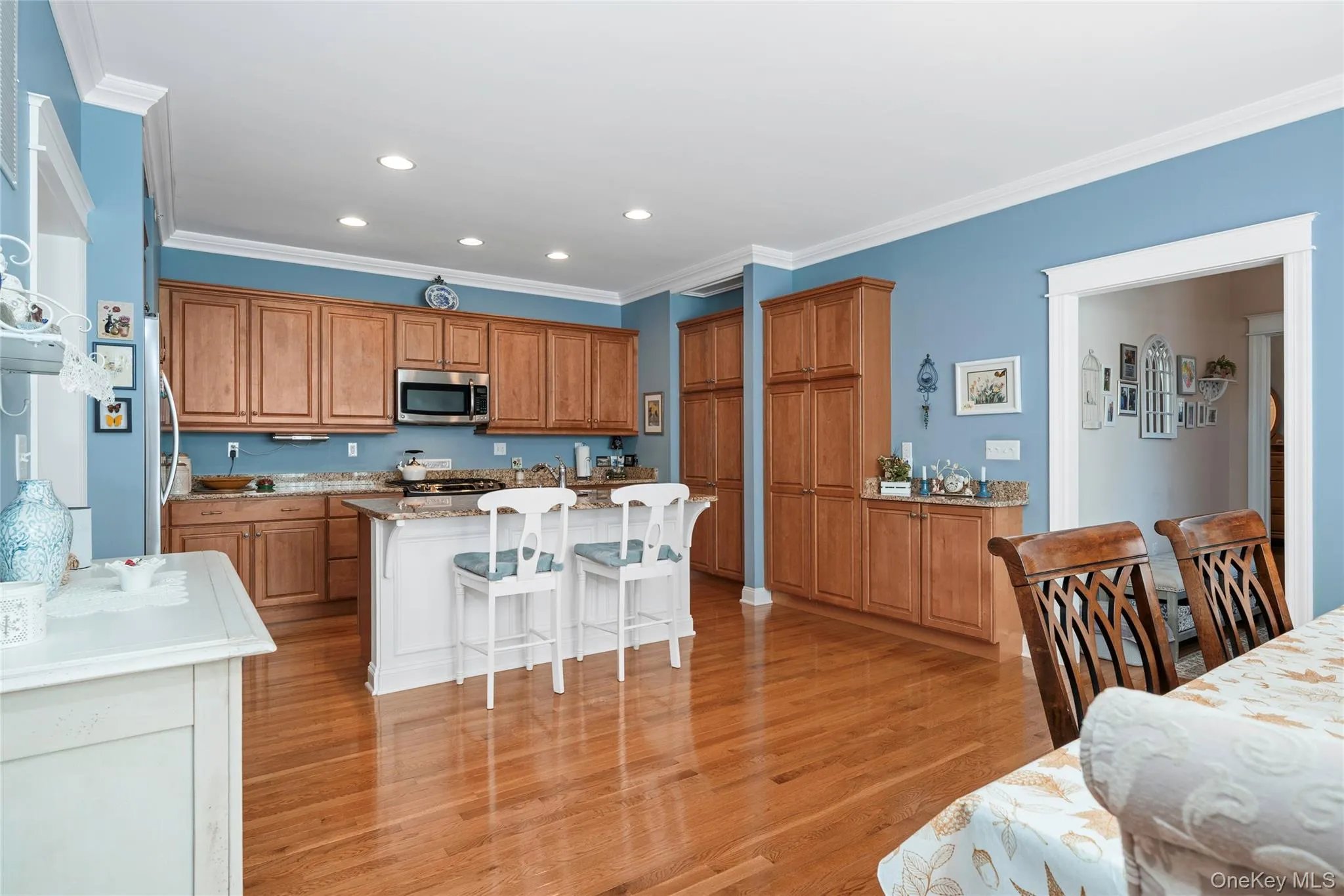 Kitchen with a kitchen bar, ornamental molding, stainless steel microwave, light wood-style floors, and light stone countertops Kitchen with a kitchen bar, ornamental molding, stainless steel microwave, light wood-style floors, and light stone countertops