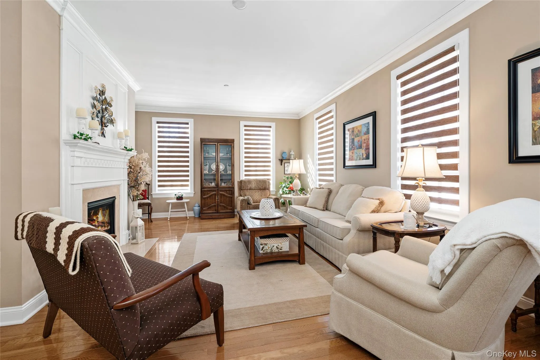 Living area with ornamental molding, a warm lit fireplace, and hardwood / wood-style floors Living area with ornamental molding, a warm lit fireplace, and hardwood / wood-style floors