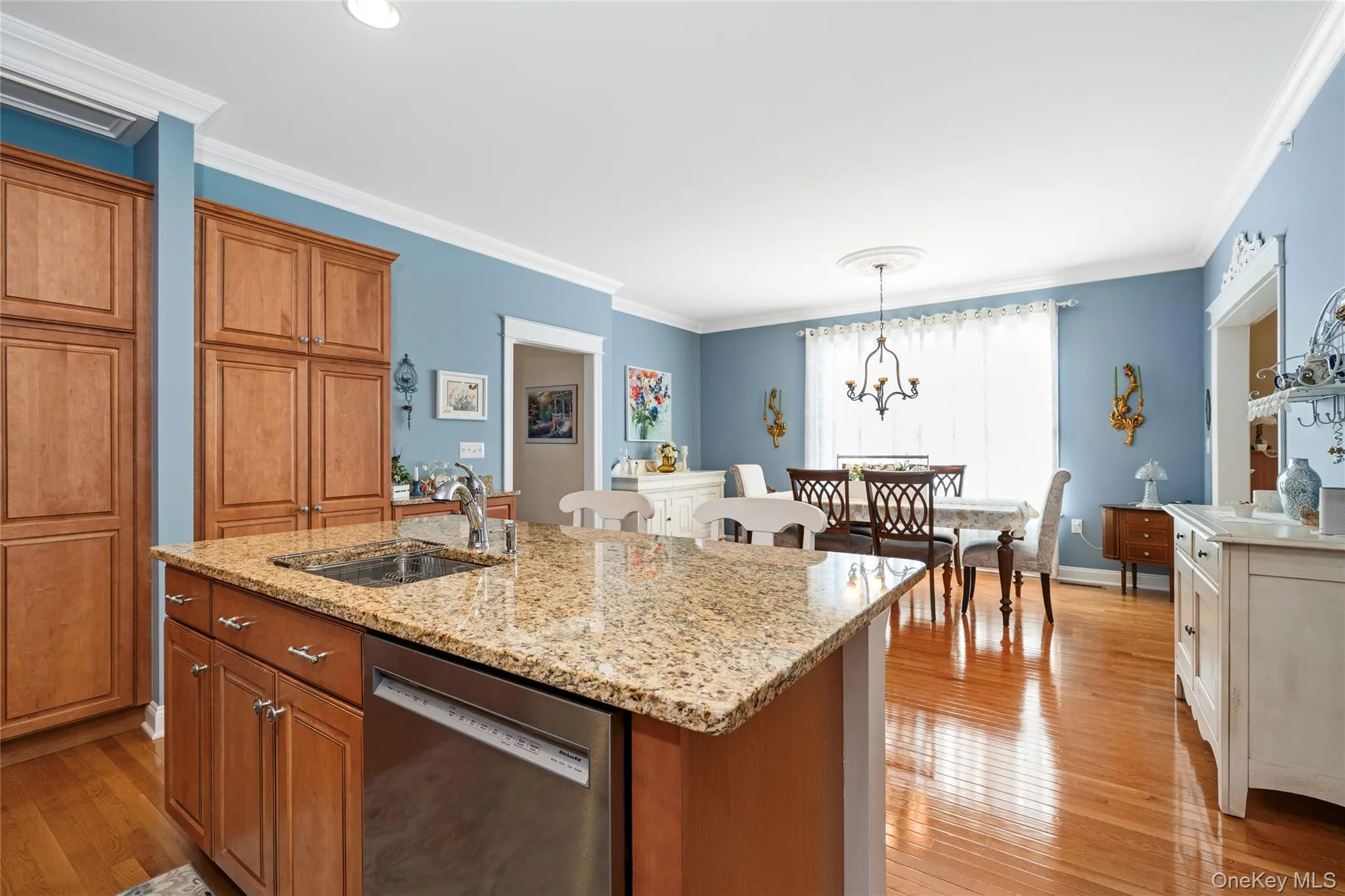 Kitchen featuring wood finish cabinets, dishwasher, light wood-style floors, light stone counters, and ornamental molding Kitchen featuring wood finish cabinets, dishwasher, light wood-style floors, light stone counters, and ornamental molding