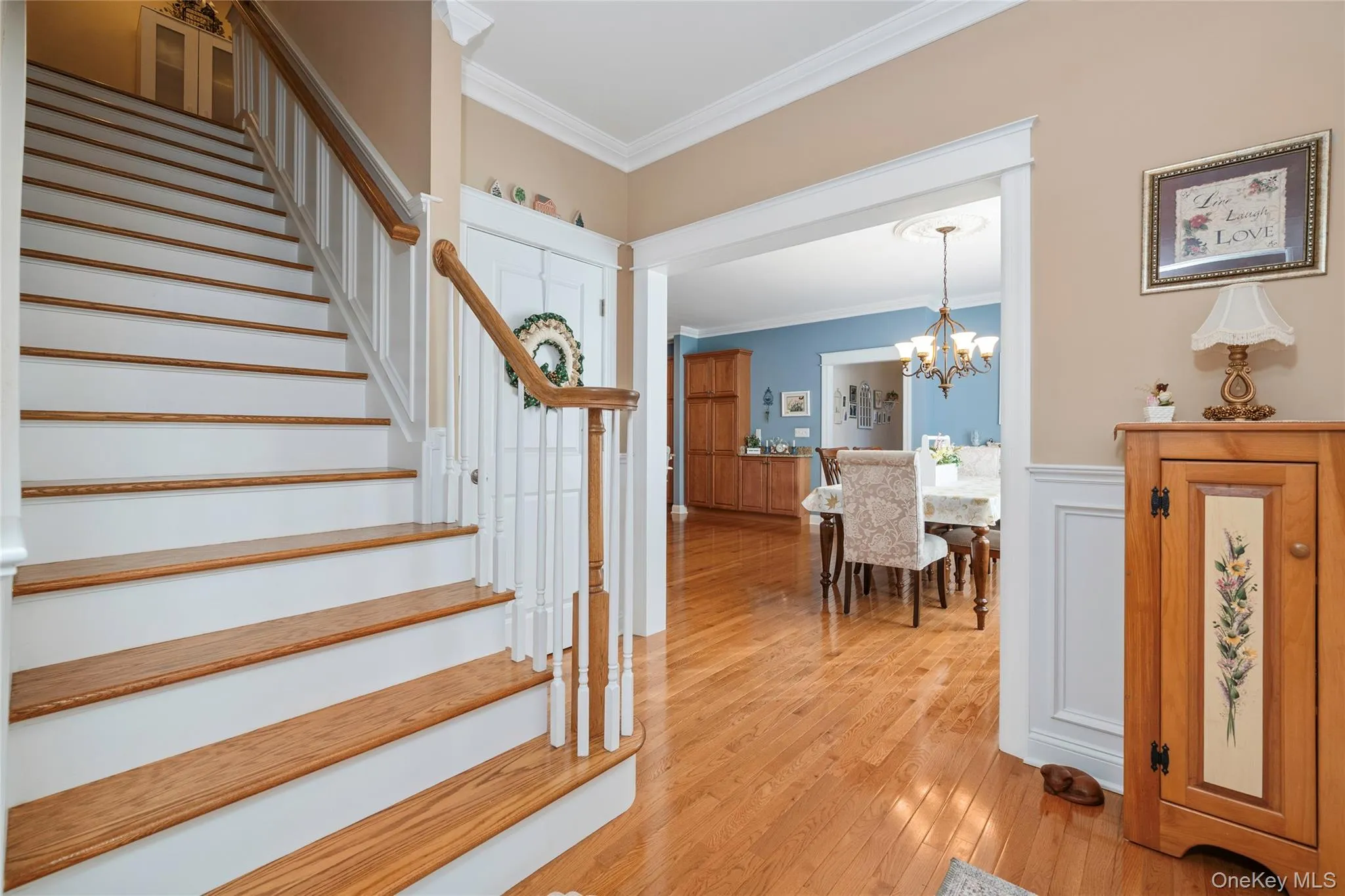 Stairway with ornamental molding, wood-type flooring, and a chandelier Stairway with ornamental molding, wood-type flooring, and a chandelier