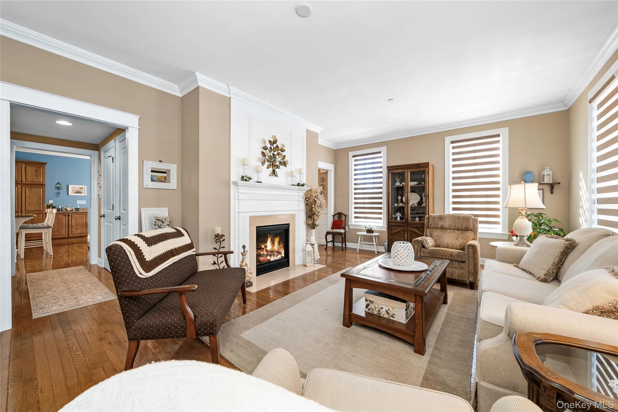 Living area with crown molding, wood-type flooring, and a fireplace with flush hearth Living area with crown molding, wood-type flooring, and a fireplace with flush hearth