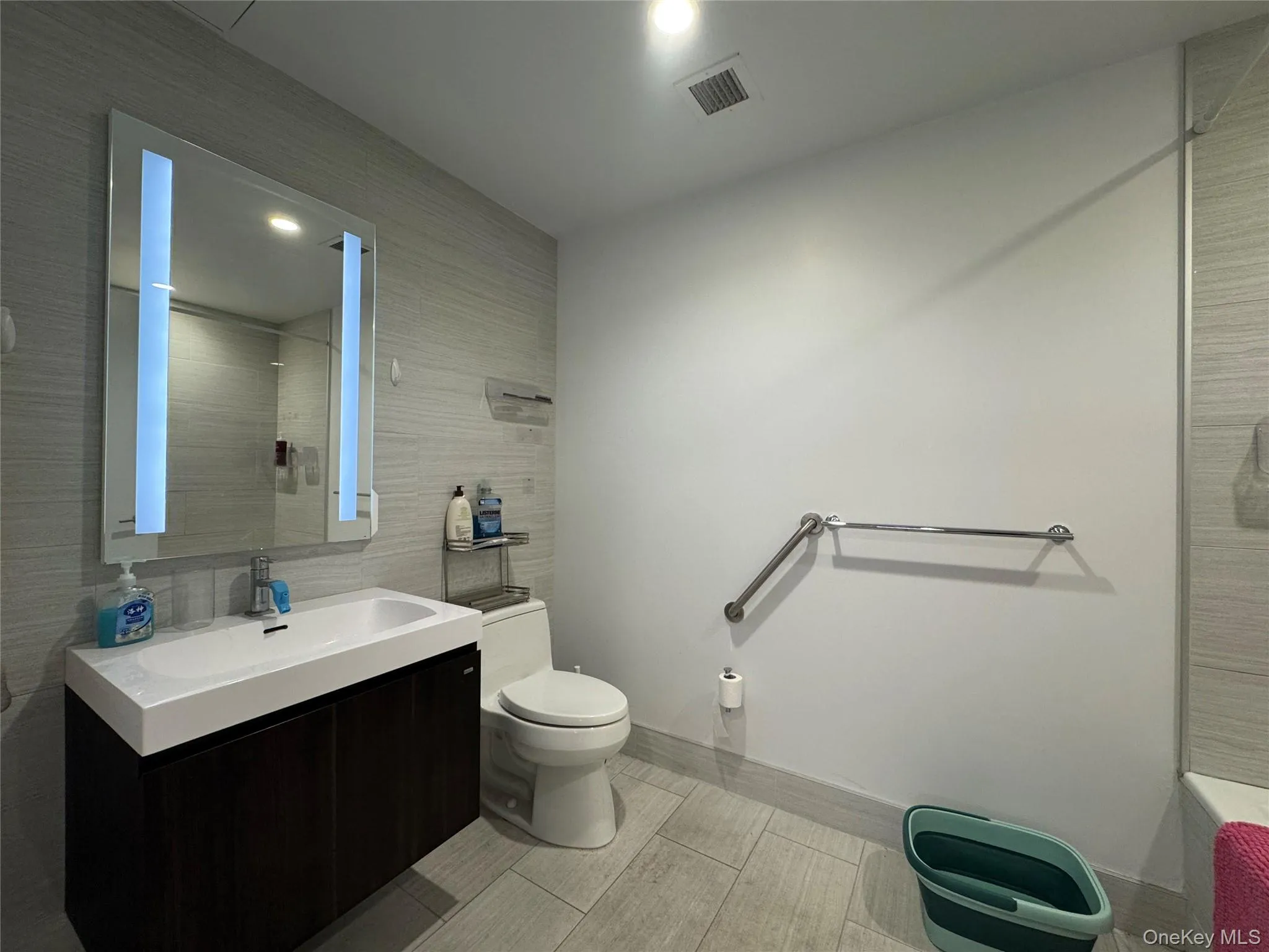 Bathroom with vanity, a shower, and tile walls Bathroom with vanity, a shower, and tile walls