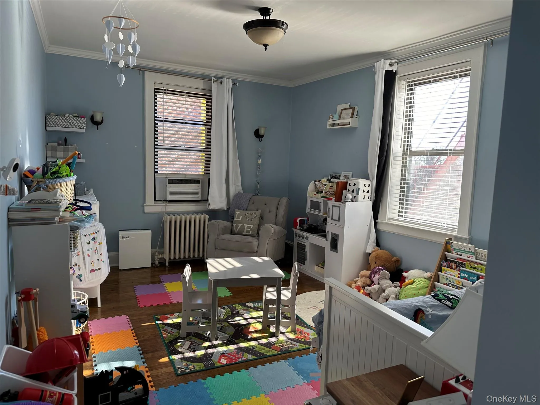 Game room featuring ornamental molding, cooling unit, dark wood-type flooring, a chandelier, and radiator heating unit Game room featuring ornamental molding, cooling unit, dark wood-type flooring, a chandelier, and radiator heating unit