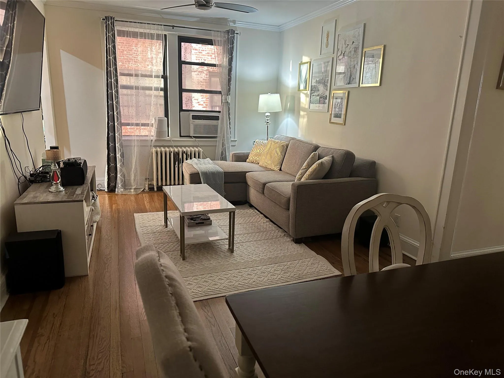 Living room with ceiling fan, light hardwood / wood-style floors, ornamental molding, and radiator Living room with ceiling fan, light hardwood / wood-style floors, ornamental molding, and radiator