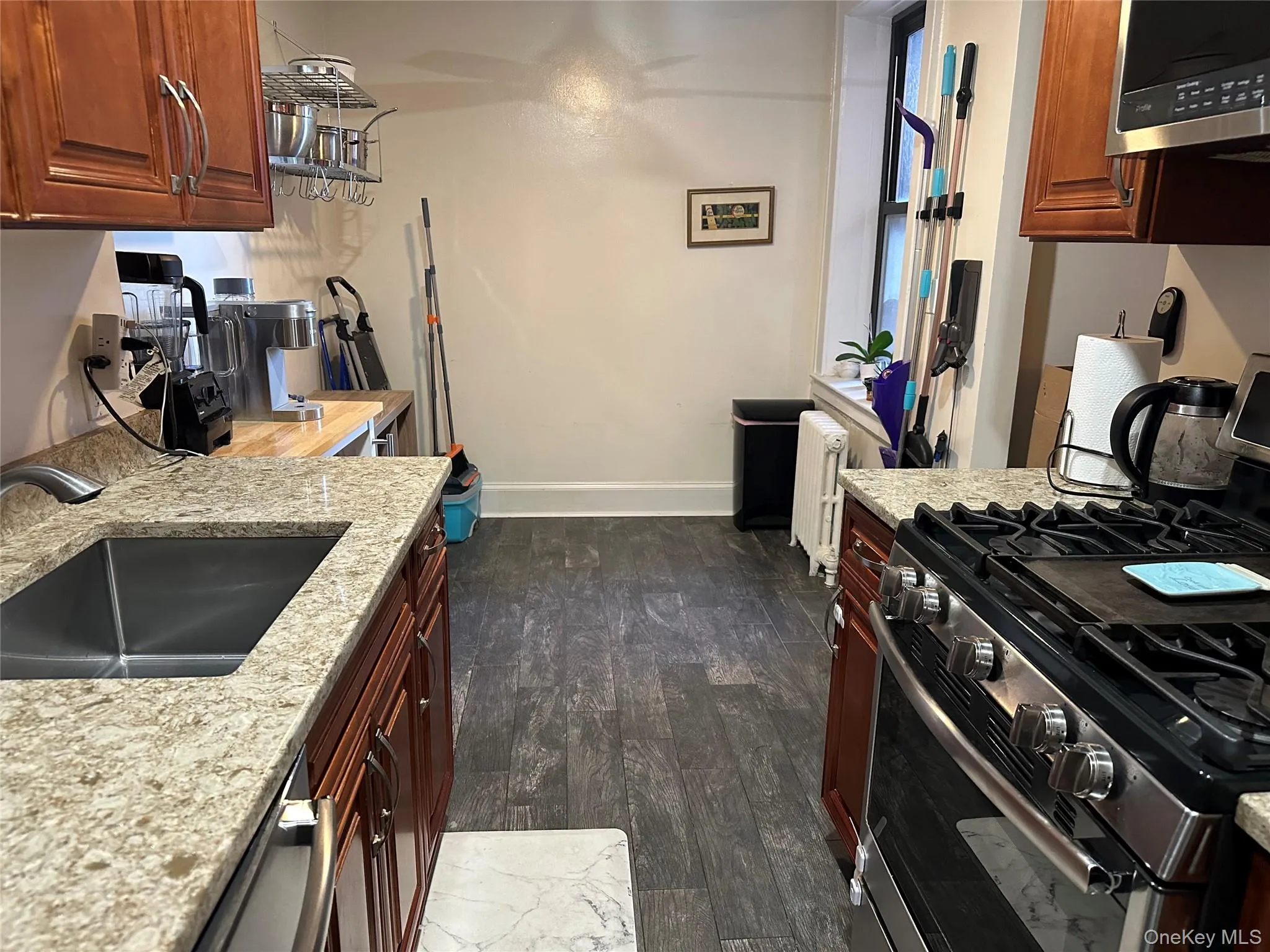 Kitchen with sink, dark hardwood / wood-style flooring, light stone countertops, and stainless steel appliances Kitchen with sink, dark hardwood / wood-style flooring, light stone countertops, and stainless steel appliances