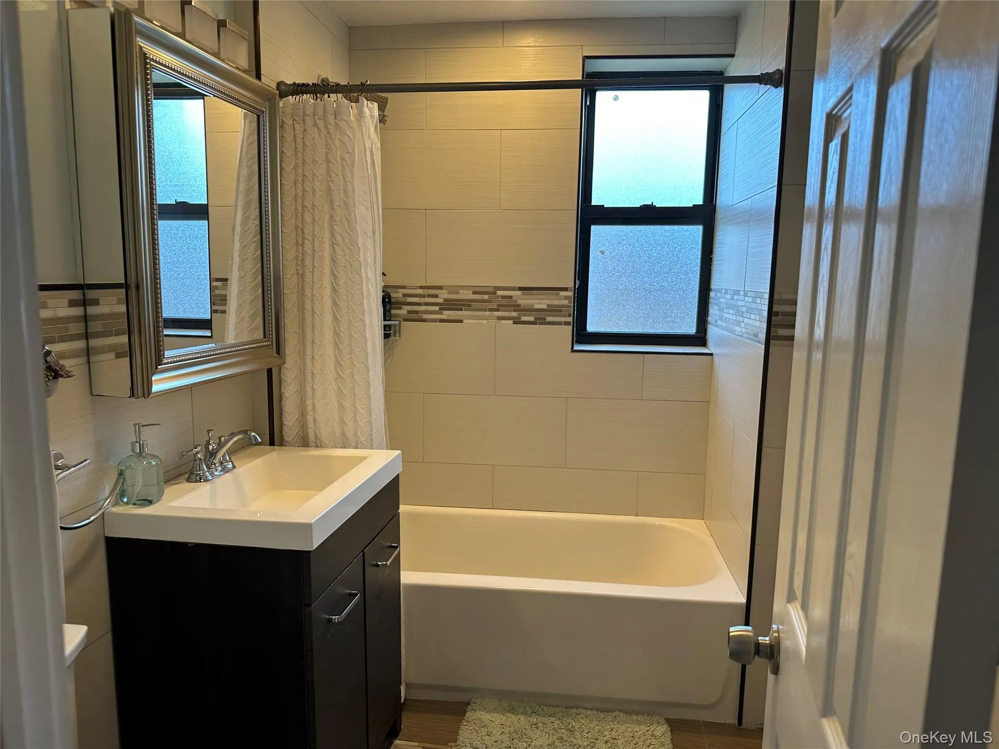 Bathroom featuring shower / tub combo with curtain and vanity Bathroom featuring shower / tub combo with curtain and vanity