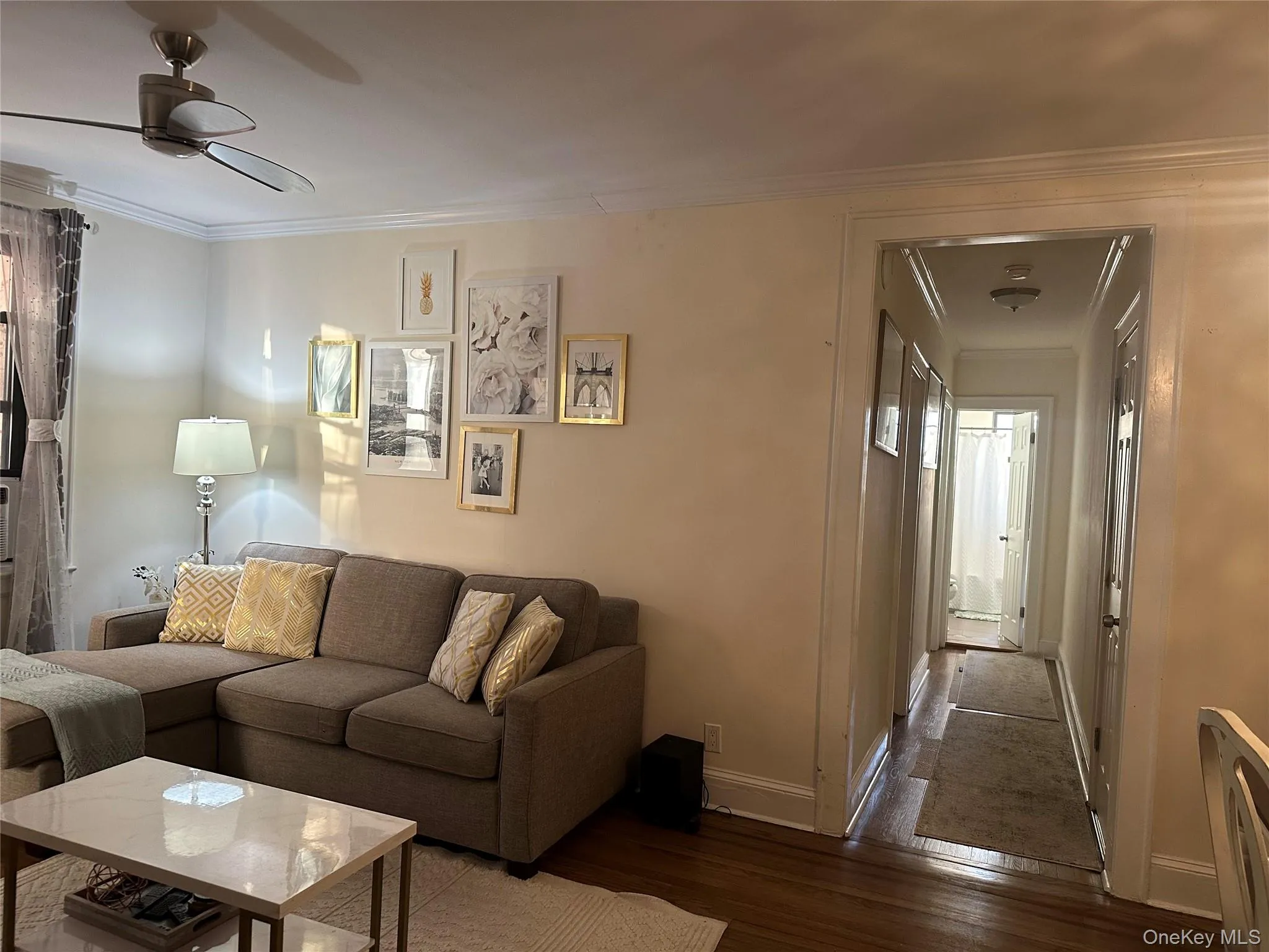 Living room with hardwood / wood-style floors, ceiling fan, and ornamental molding Living room with hardwood / wood-style floors, ceiling fan, and ornamental molding