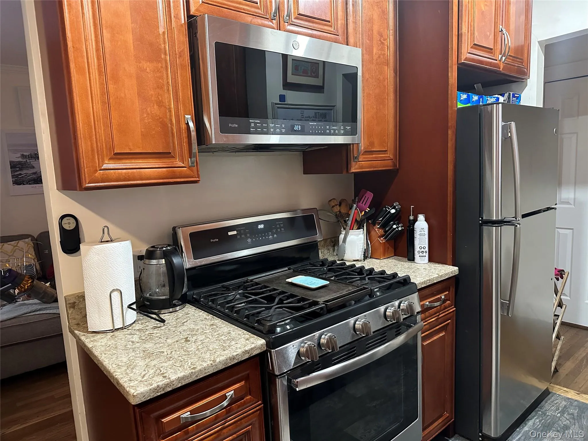 Kitchen featuring light stone countertops, dark hardwood / wood-style flooring, and appliances with stainless steel finishes Kitchen featuring light stone countertops, dark hardwood / wood-style flooring, and appliances with stainless steel finishes