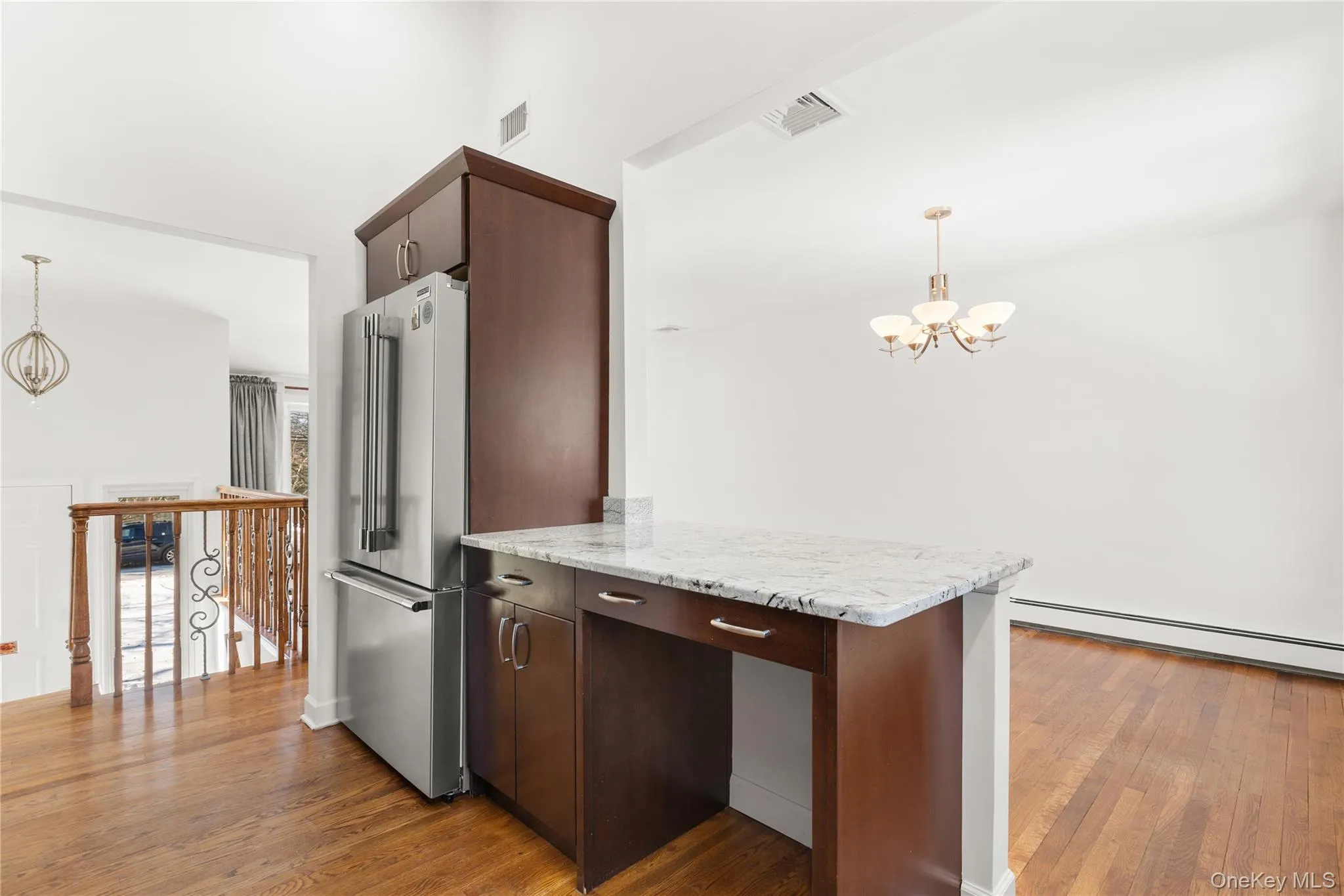 Kitchen featuring suspended lighting, dark wood finish cabinets, high end refrigerator, and wood flooring Kitchen featuring suspended lighting, dark wood finish cabinets, high end refrigerator, and wood flooring