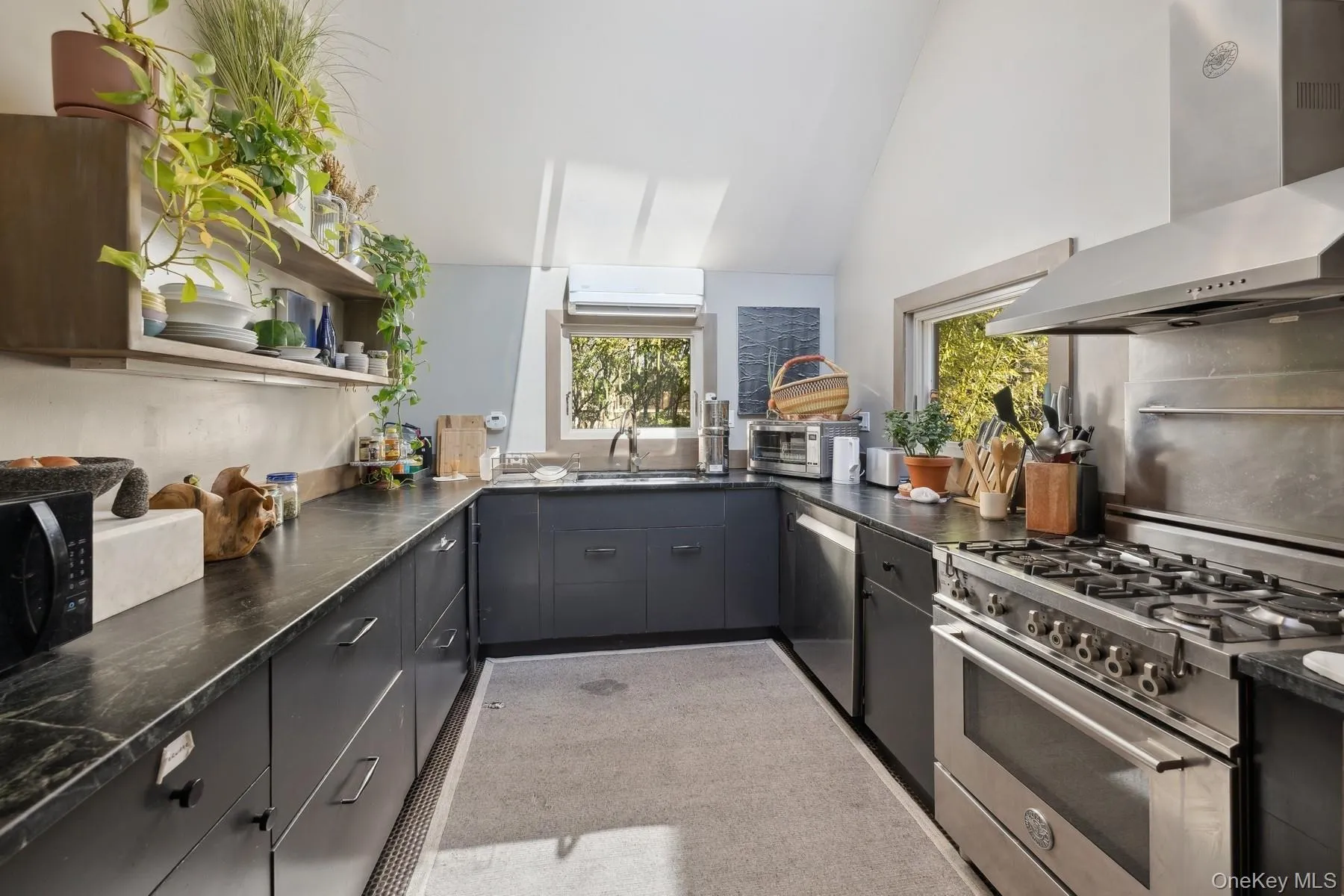 Kitchen featuring sink, wall chimney exhaust hood, lofted ceiling, kitchen peninsula, and appliances with stainless steel finishes Kitchen featuring sink, wall chimney exhaust hood, lofted ceiling, kitchen peninsula, and appliances with stainless steel finishes