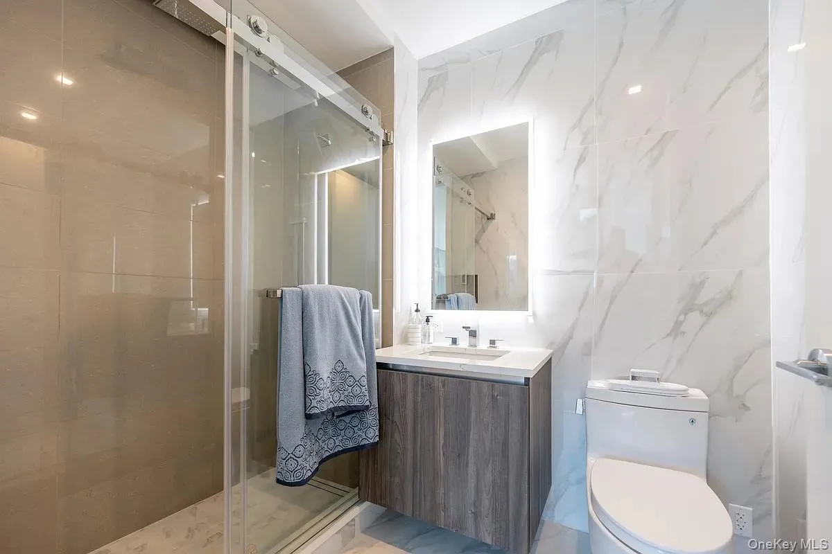 Full bath featuring toilet, tile walls, a stall shower, and vanity Full bath featuring toilet, tile walls, a stall shower, and vanity