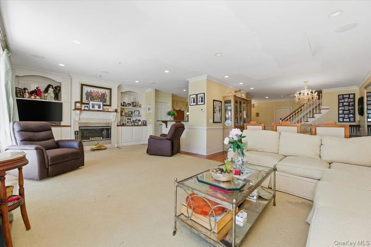 Living area with built in features, hanging lights, ornamental molding, carpet, and a fireplace with flush hearth Living area with built in features, hanging lights, ornamental molding, carpet, and a fireplace with flush hearth