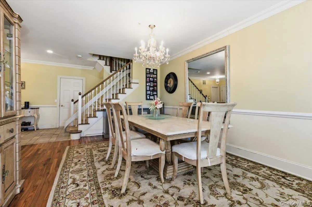 Dining space featuring ornamental molding, a chandelier, dark wood finished floors, and a wainscoted wall Dining space featuring ornamental molding, a chandelier, dark wood finished floors, and a wainscoted wall
