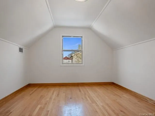 Additional living space featuring baseboards, visible vents, light wood-style floors, and vaulted ceiling Additional living space featuring baseboards, visible vents, light wood-style floors, and vaulted ceiling