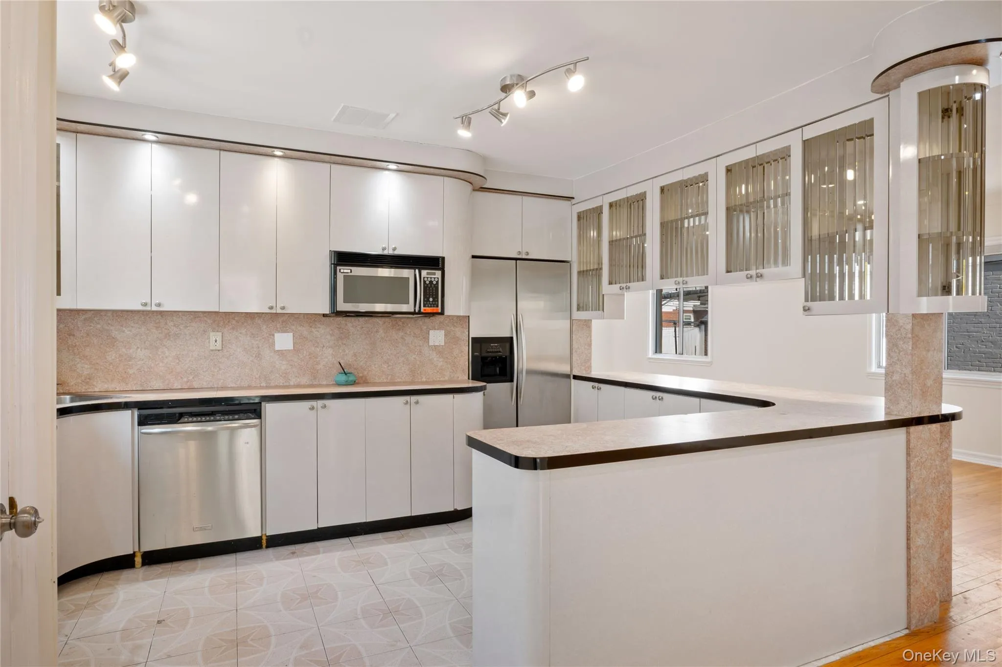 Kitchen featuring white cabinets, backsplash, visible vents, glass insert cabinets, and appliances with stainless steel finishes Kitchen featuring white cabinets, backsplash, visible vents, glass insert cabinets, and appliances with stainless steel finishes
