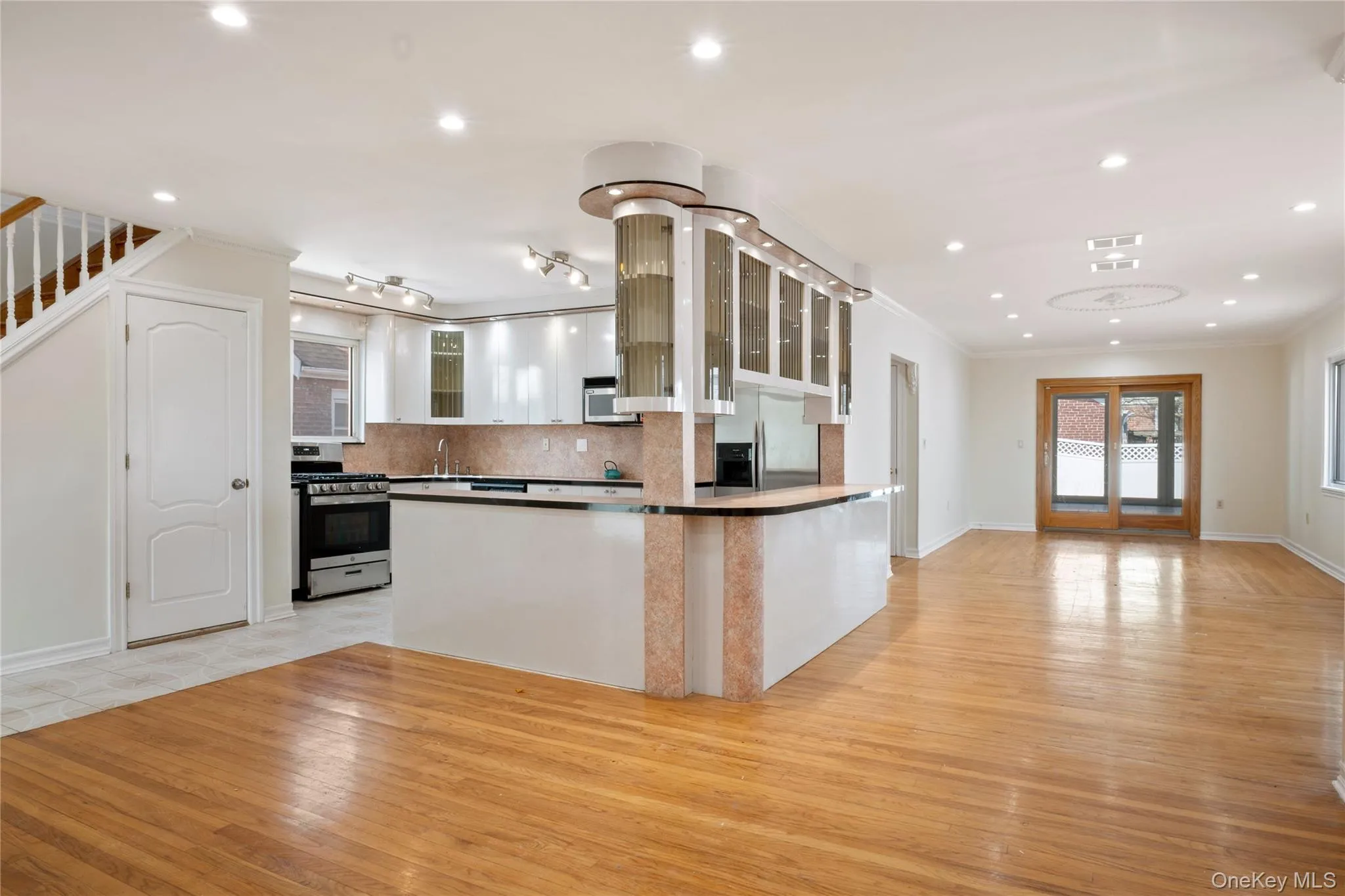 Kitchen featuring a sink, light wood-type flooring, glass insert cabinets, appliances with stainless steel finishes, and ornamental molding Kitchen featuring a sink, light wood-type flooring, glass insert cabinets, appliances with stainless steel finishes, and ornamental molding