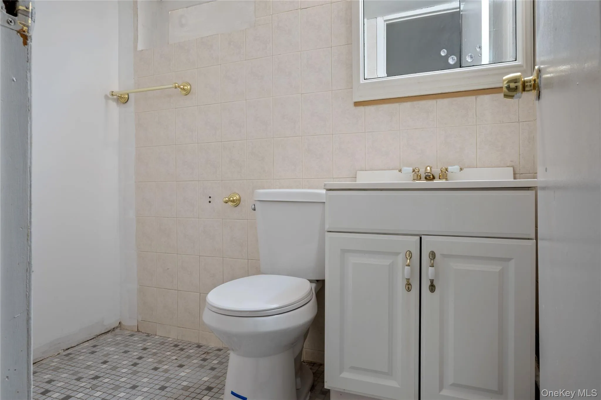 Bathroom featuring tile walls, tile patterned floors, vanity, and toilet Bathroom featuring tile walls, tile patterned floors, vanity, and toilet