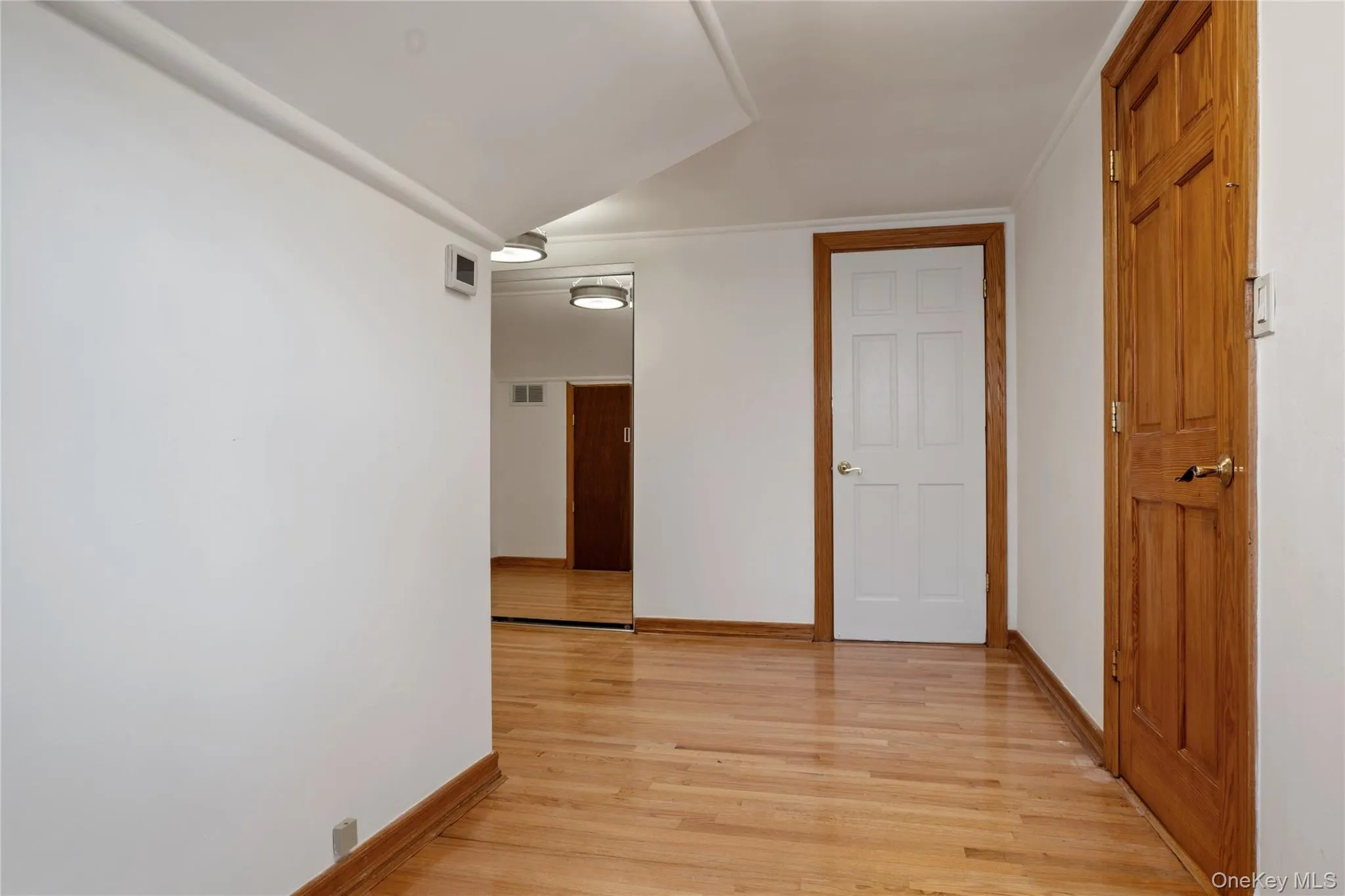 Corridor featuring light wood-style floors, baseboards, and visible vents Corridor featuring light wood-style floors, baseboards, and visible vents
