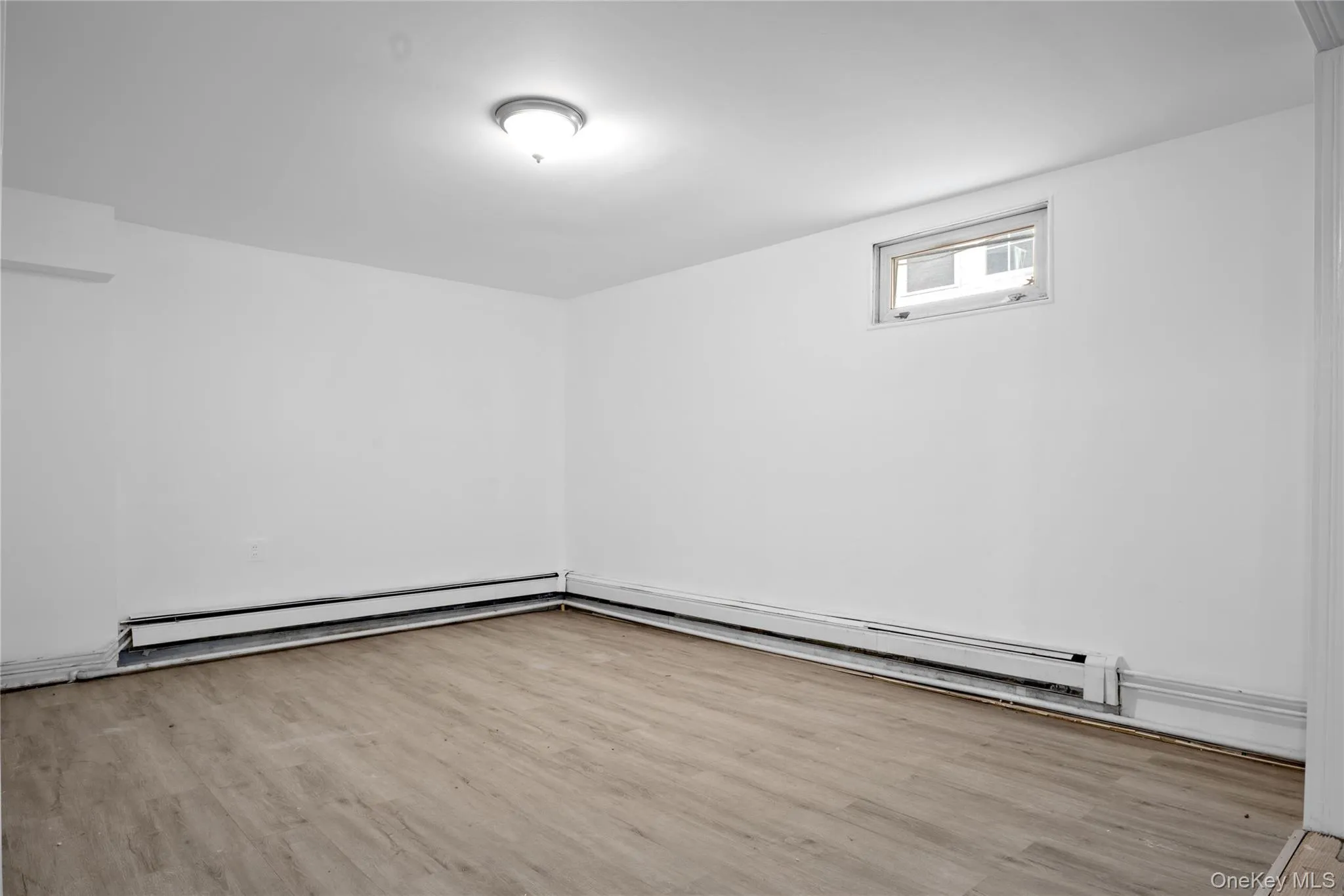 Empty room featuring a baseboard heating unit and wood finished floors Empty room featuring a baseboard heating unit and wood finished floors