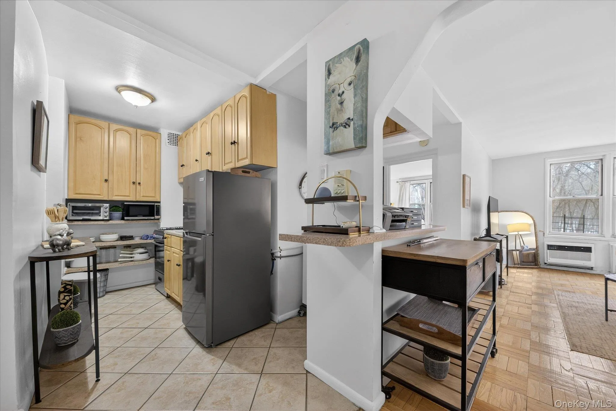 Kitchen featuring light wood finish cabinets, refrigerator, light countertops, and stainless steel microwave Kitchen featuring light wood finish cabinets, refrigerator, light countertops, and stainless steel microwave