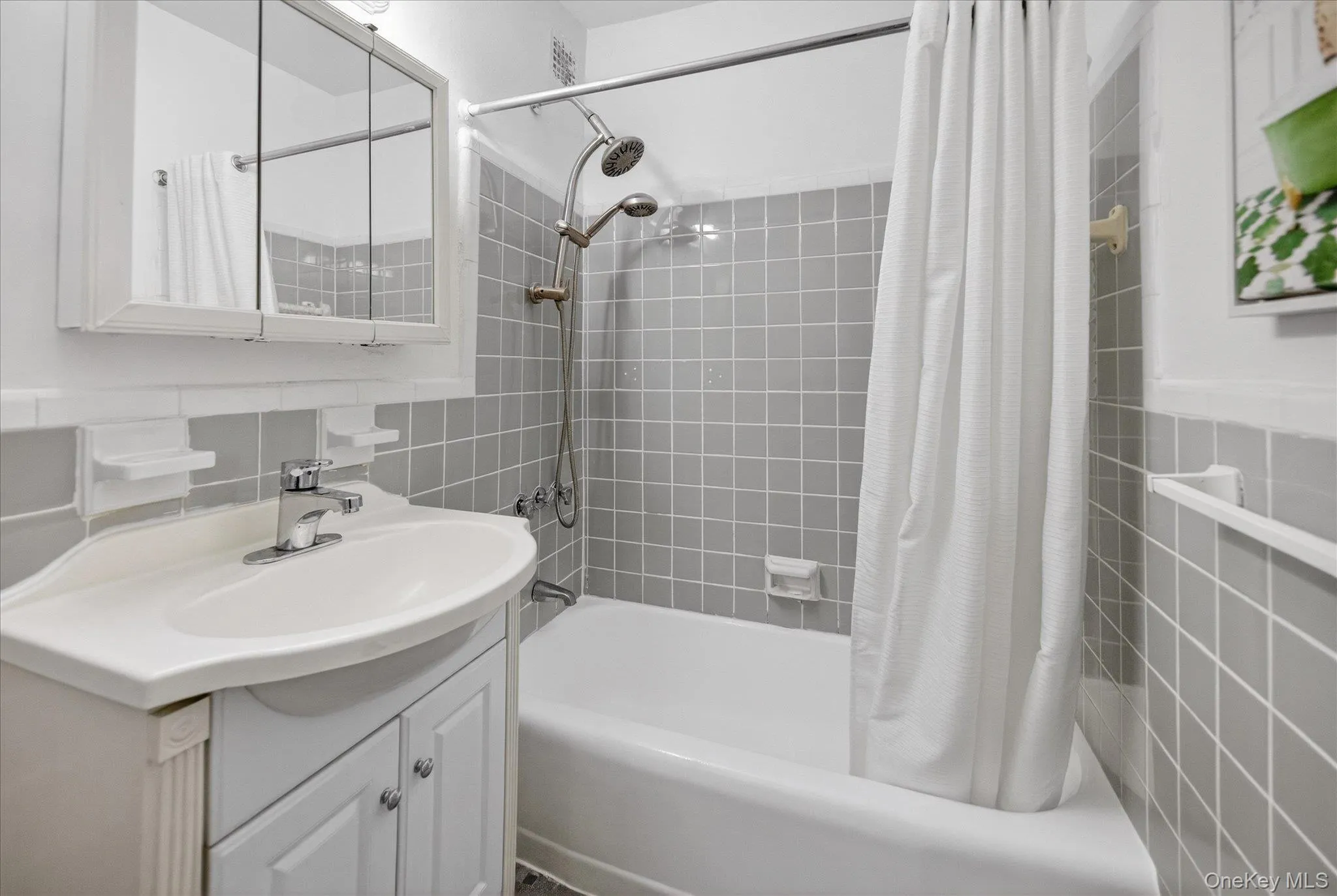 Full bath featuring tile walls, shower / bath combination with curtain, vanity, and tasteful backsplash Full bath featuring tile walls, shower / bath combination with curtain, vanity, and tasteful backsplash