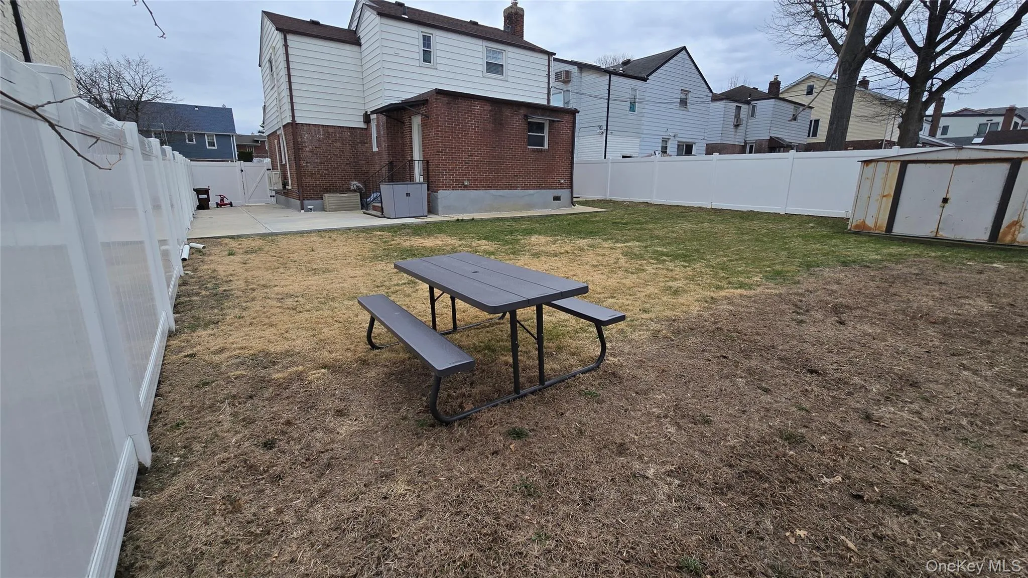 Rear view of property with brick siding, a fenced backyard, a storage unit, and a residential view Rear view of property with brick siding, a fenced backyard, a storage unit, and a residential view