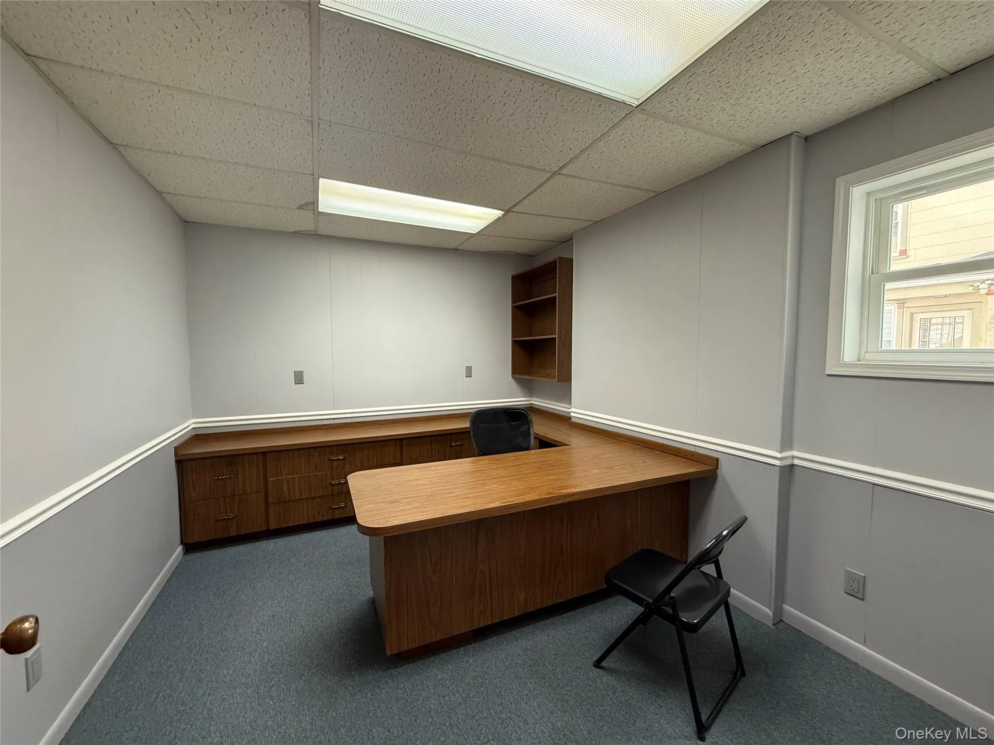 Unfurnished office with a paneled ceiling and dark carpet Unfurnished office with a paneled ceiling and dark carpet