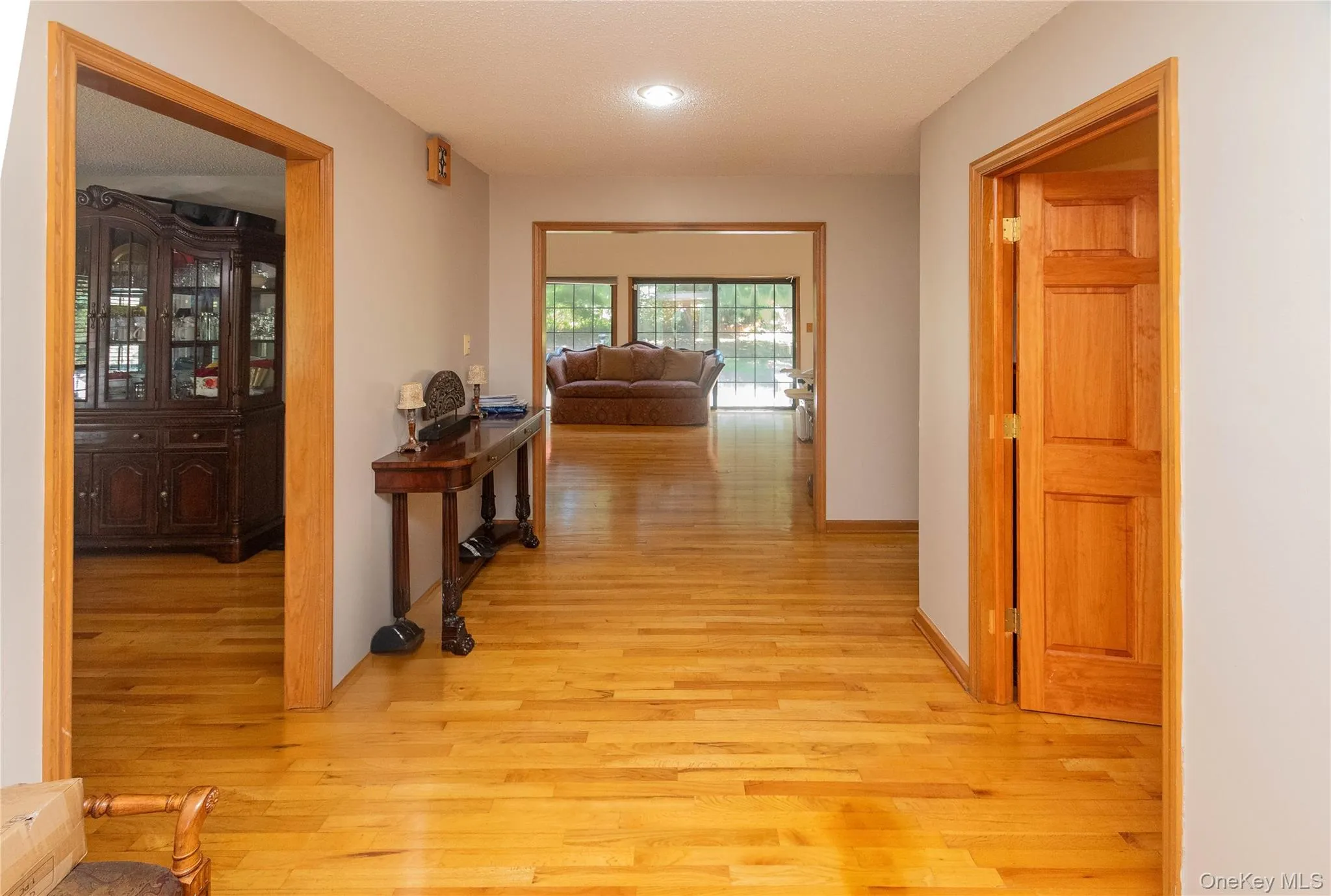 Hall featuring light wood finished floors and a textured ceiling Hall featuring light wood finished floors and a textured ceiling
